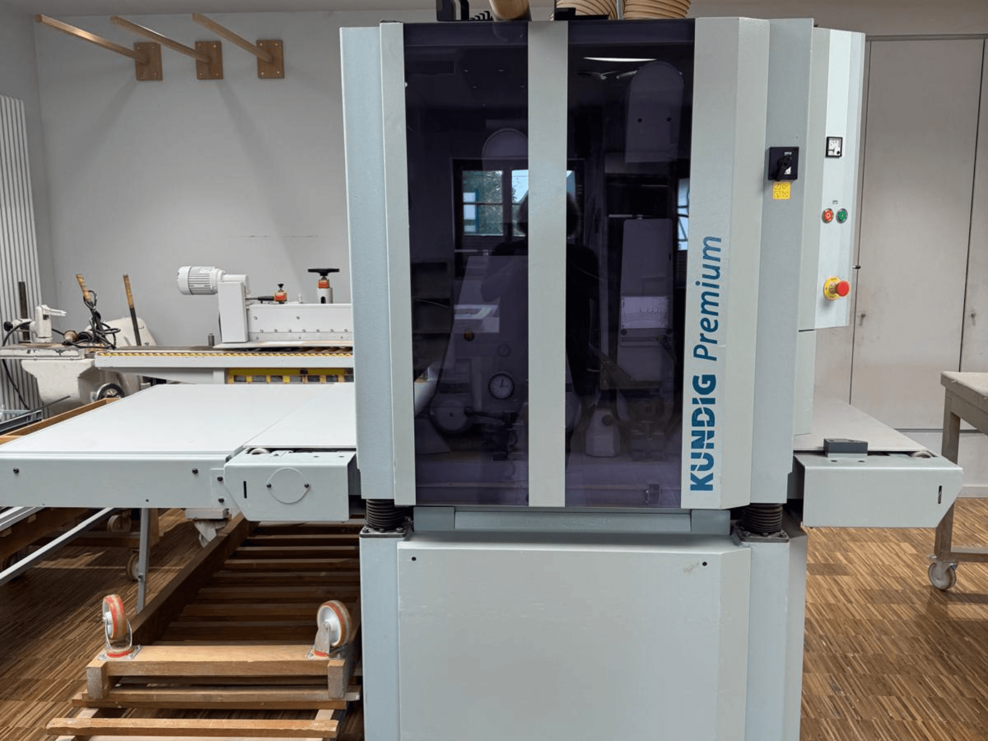 Стрічкова шліфувальна машина Kundig Premium 2-1100-RP спереду з панеллю керування та великим скляним корпусом для огляду.