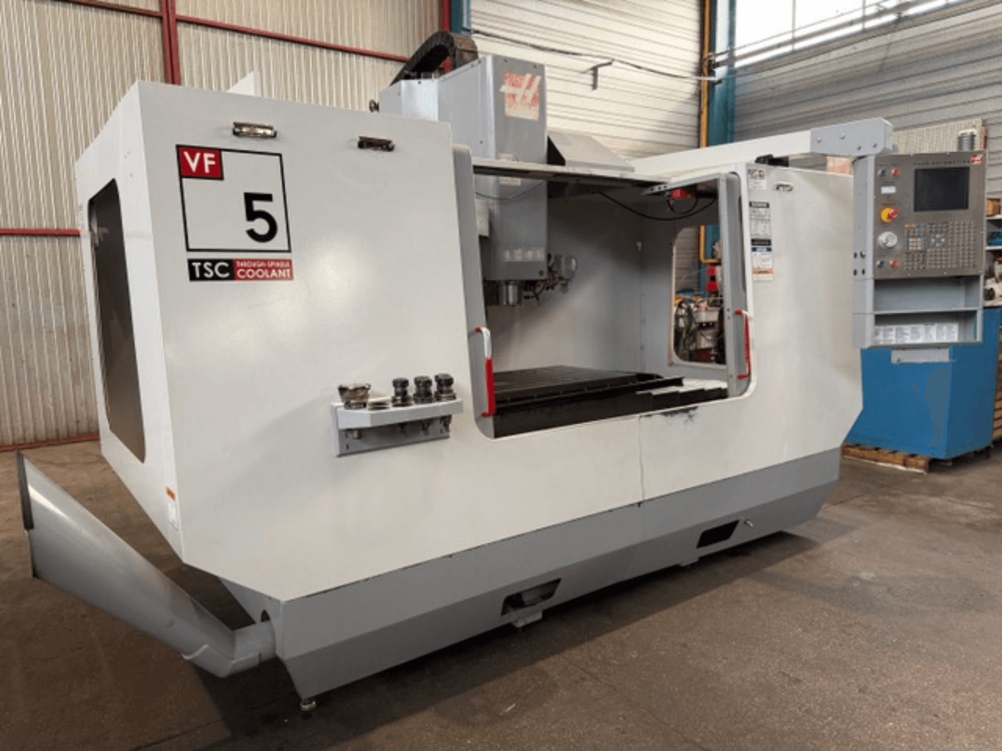 Вертикальний обробний центр HAAS VF5-HE, вид спереду, на якому видно систему охолодження TSC та панель управління оператора.