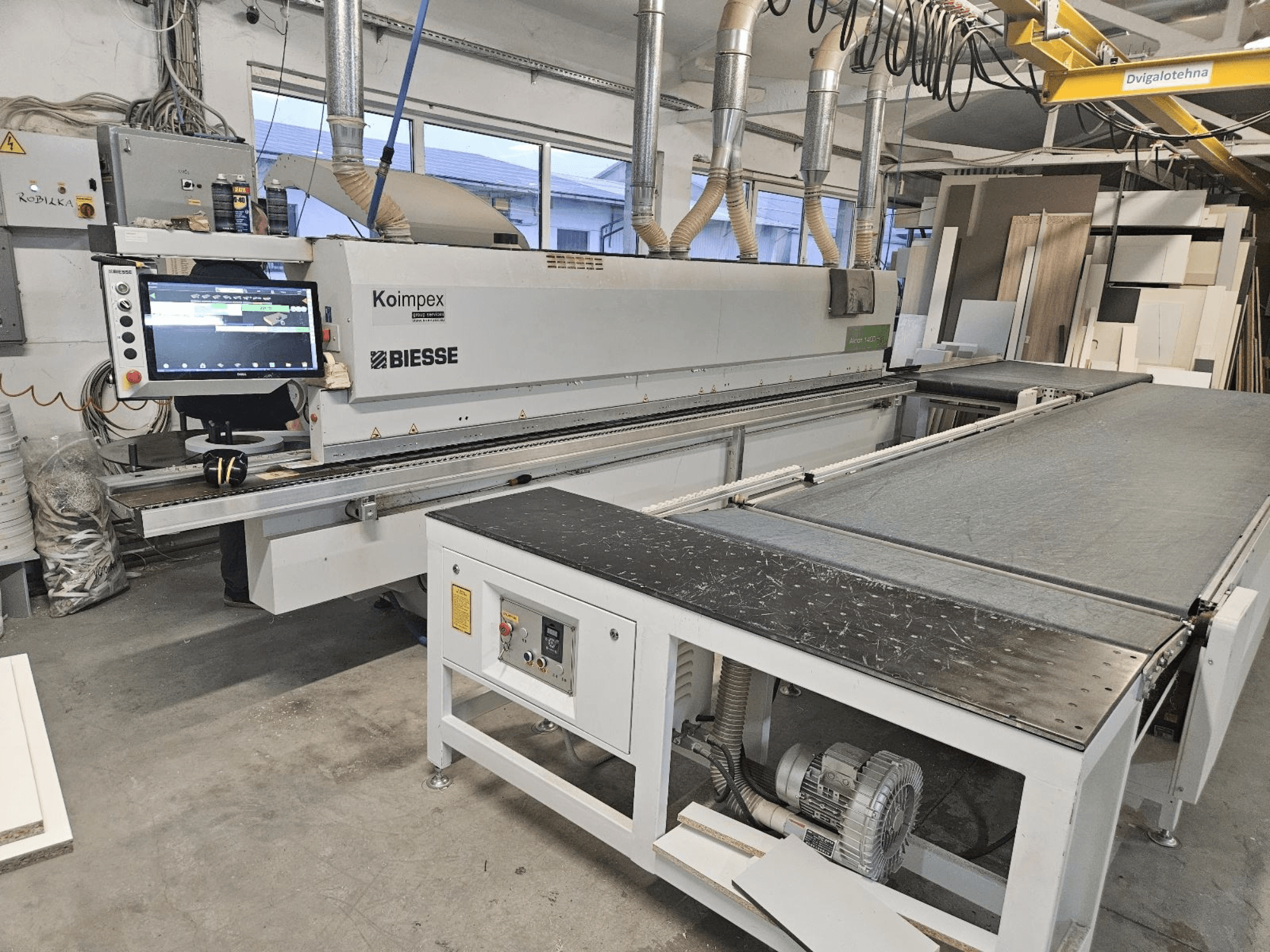 Кромкооблицювальний верстат BIESSE Akron 1440 у майстерні, вид збоку: панель керування та конвеєрна стрічка.