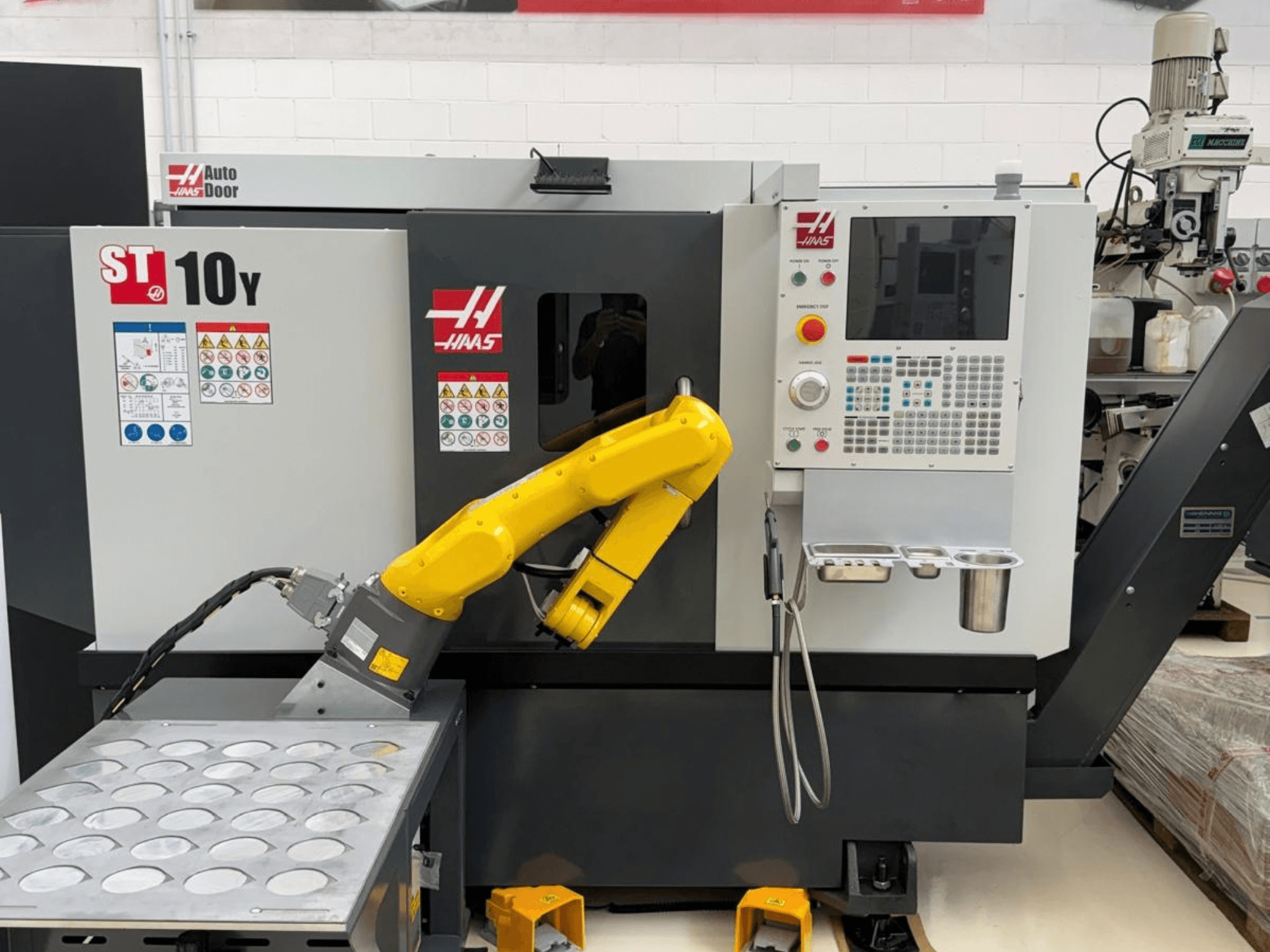Горизонтальний токарний верстат Haas ST-10Y, вид спереду, з роботом-маніпулятором та панеллю керування з лотками для інструментів.