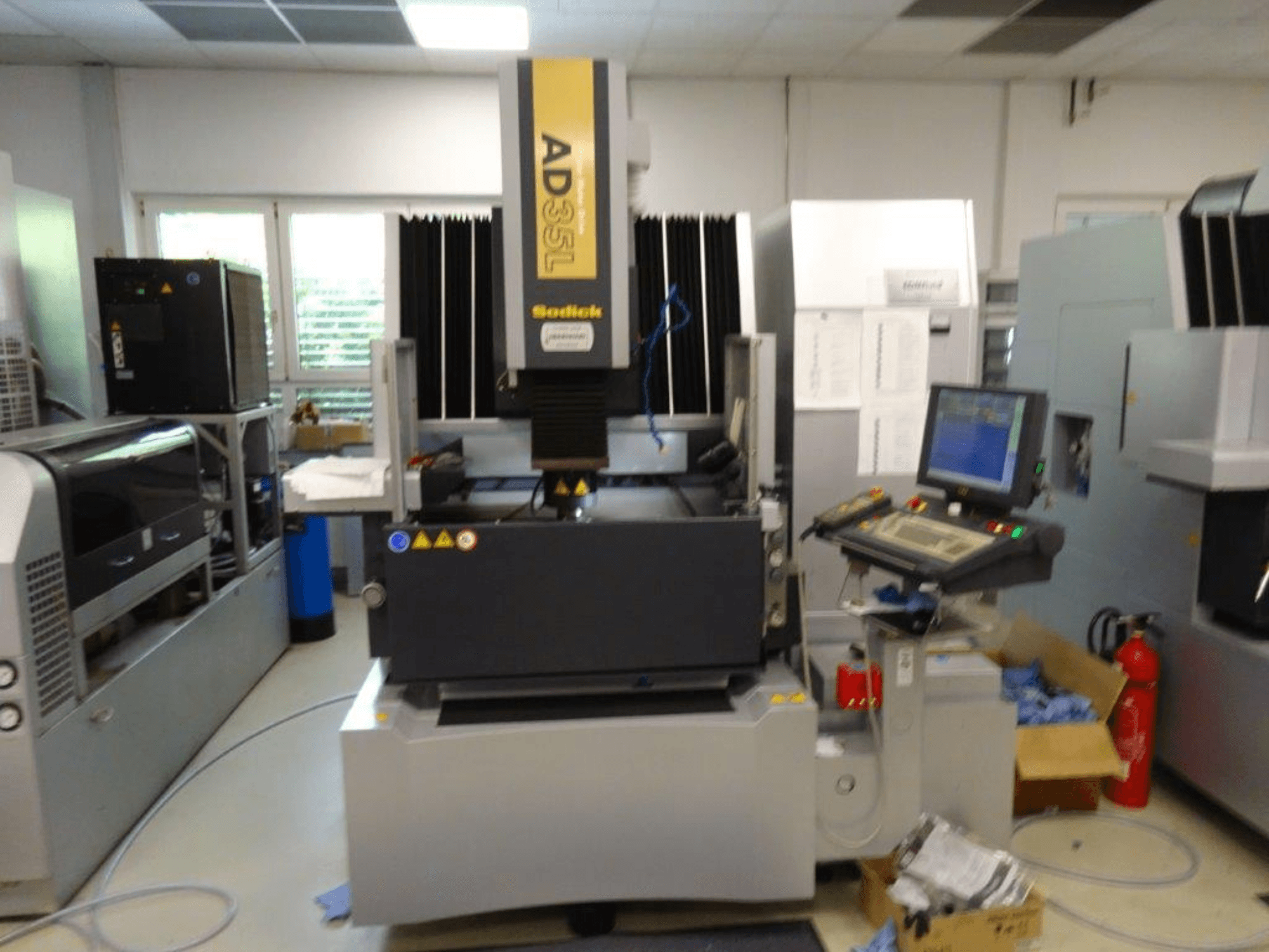 Верстат з ЧПК Sodick AD35L спереду, з панеллю керування, блоком охолодження та індикаторами безпеки.