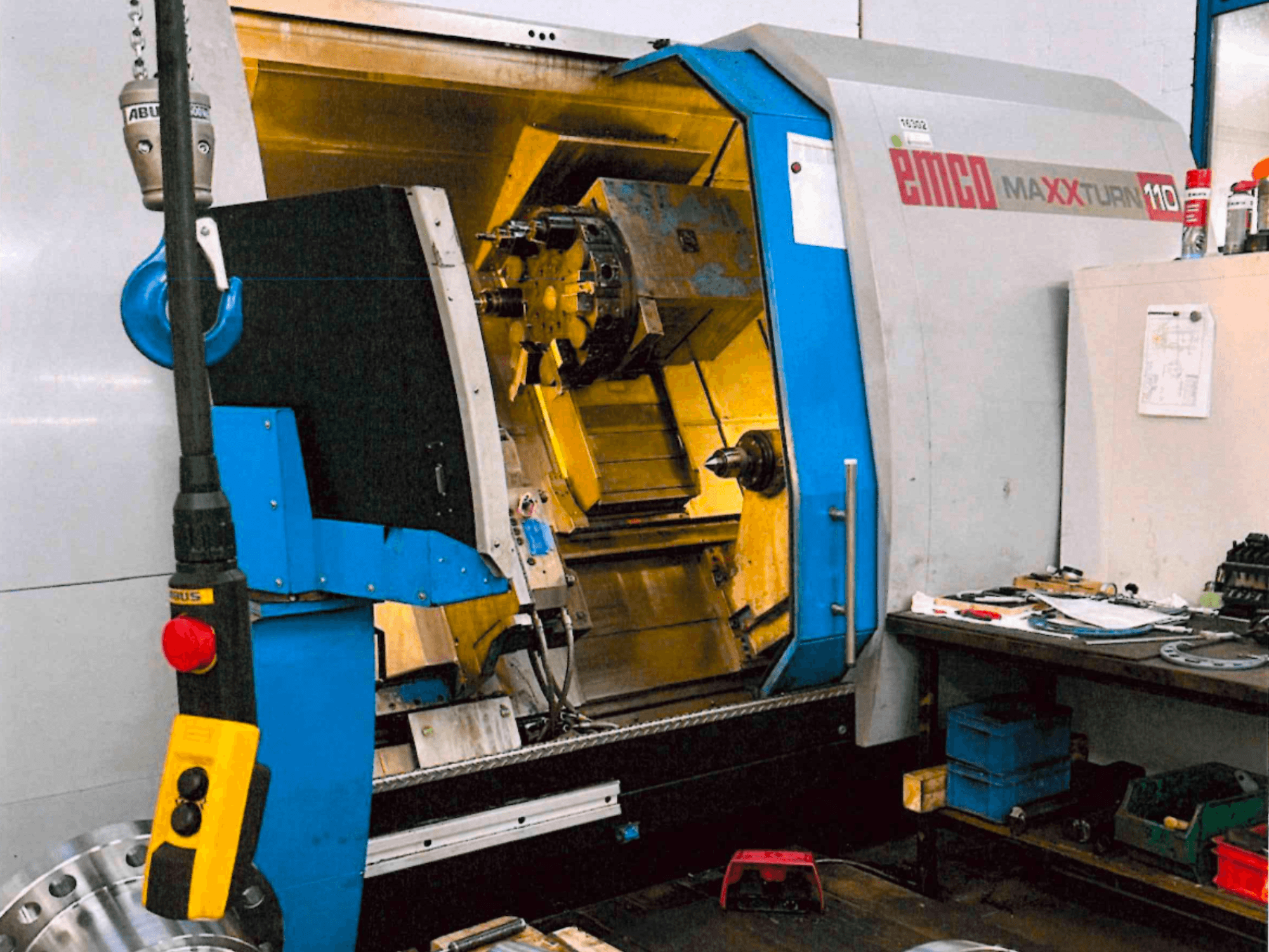 Горизонтальний токарний верстат EMCO MAXTURN 110, вид спереду, на якому видно внутрішні компоненти та панель керування, у цехових умовах.