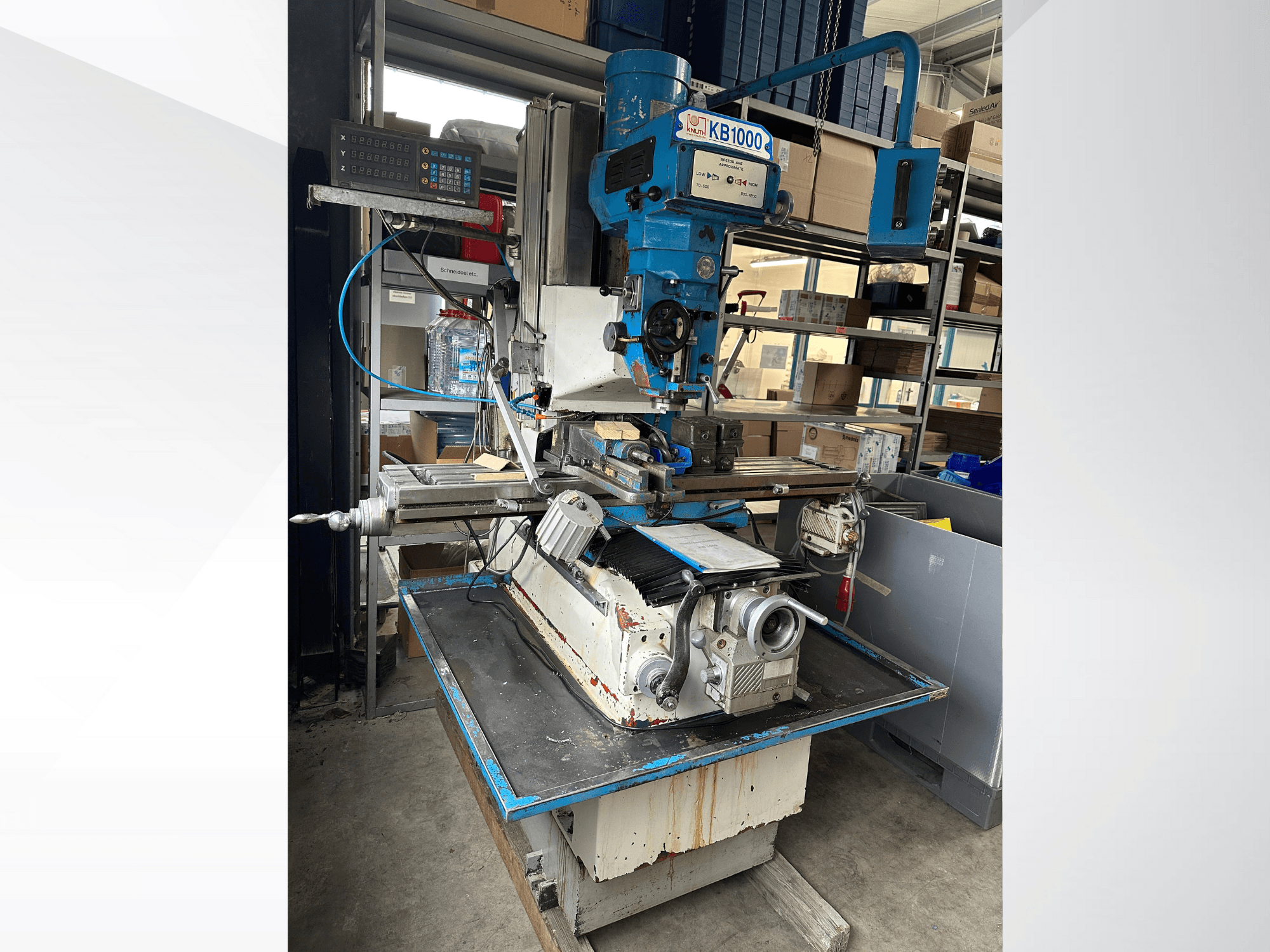 Вертикальний фрезерний верстат KB1000 з цифровим дисплеєм, вид збоку, що демонструє стіл, шпиндель та тримач інструменту.