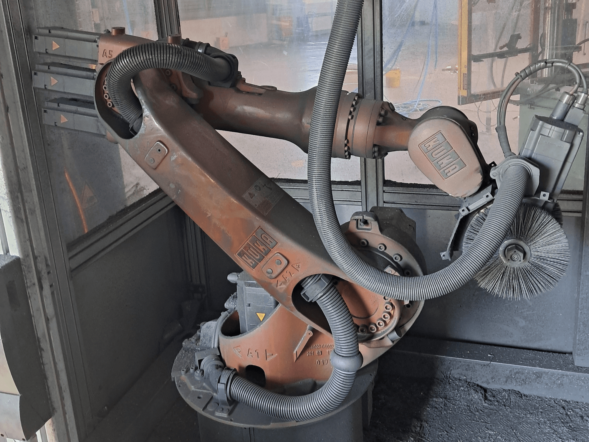 Роботизована рука KUKA KR 16-2 у боковому ракурсі, на якій видно кабелі, щітки та механічні з’єднання, у робочому середовищі.