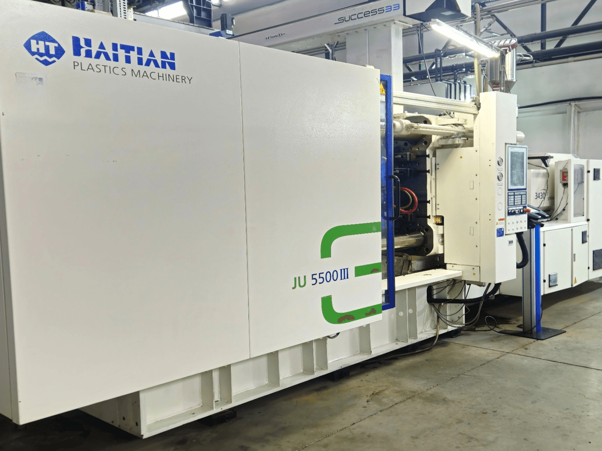 Машина для виготовлення пластмасових виробів Haitian JU 5500III у заводських умовах, вид спереду, що демонструє панель управління та виробничу зону.