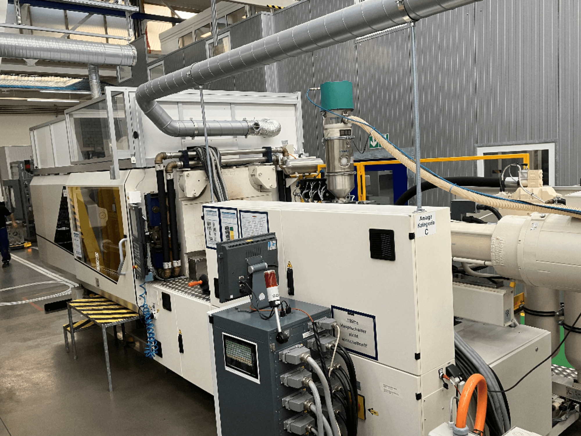 Машина для лиття під тиском, вигляд спереду, з фірмовою етикеткою, панеллю керування та видимими шлангами у заводських умовах.