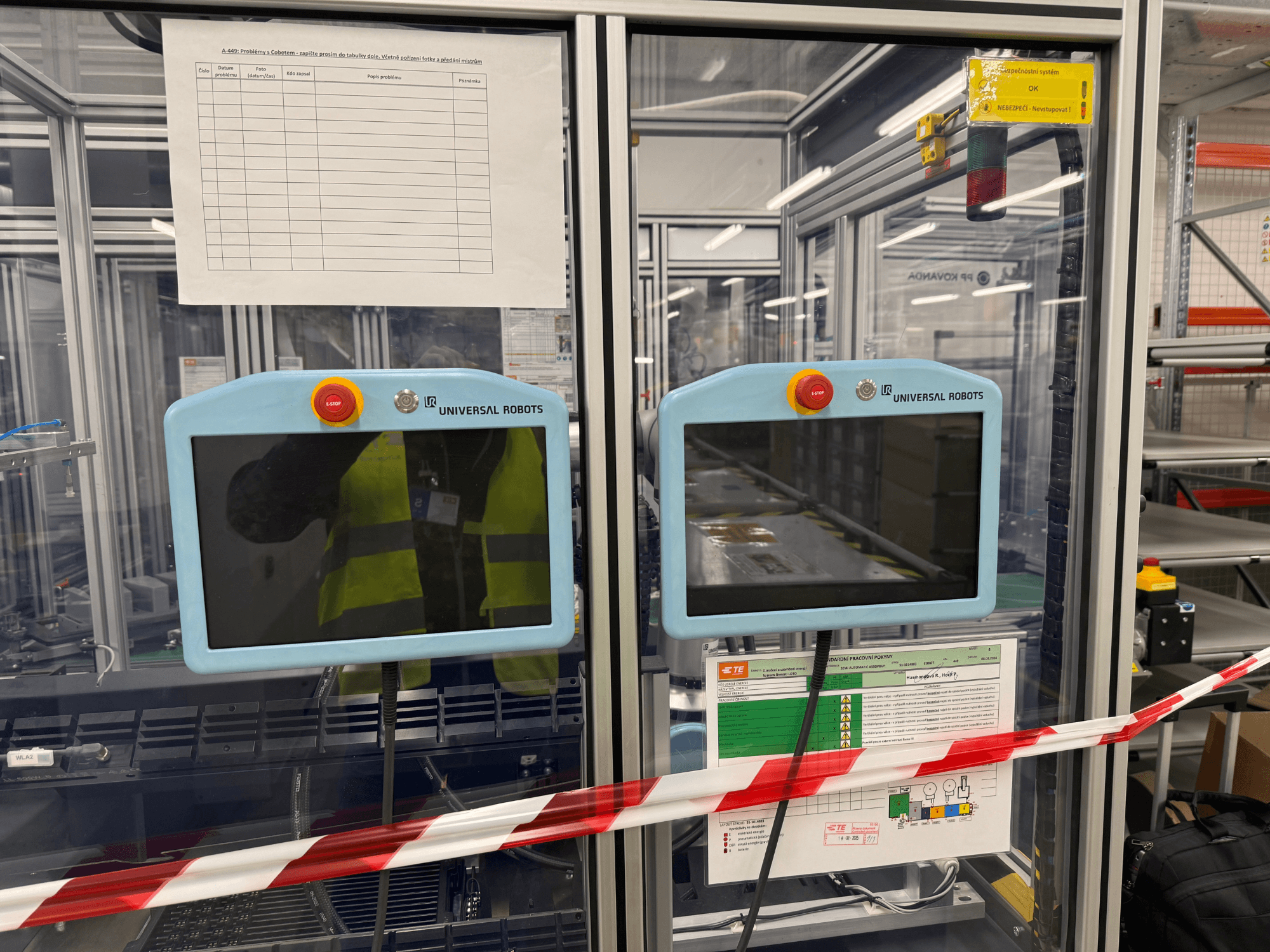 Панель керування маніпулятором робота Universal Robots UR5 e з двома моніторами, кнопками аварійної зупинки та інструкціями з техніки безпеки.