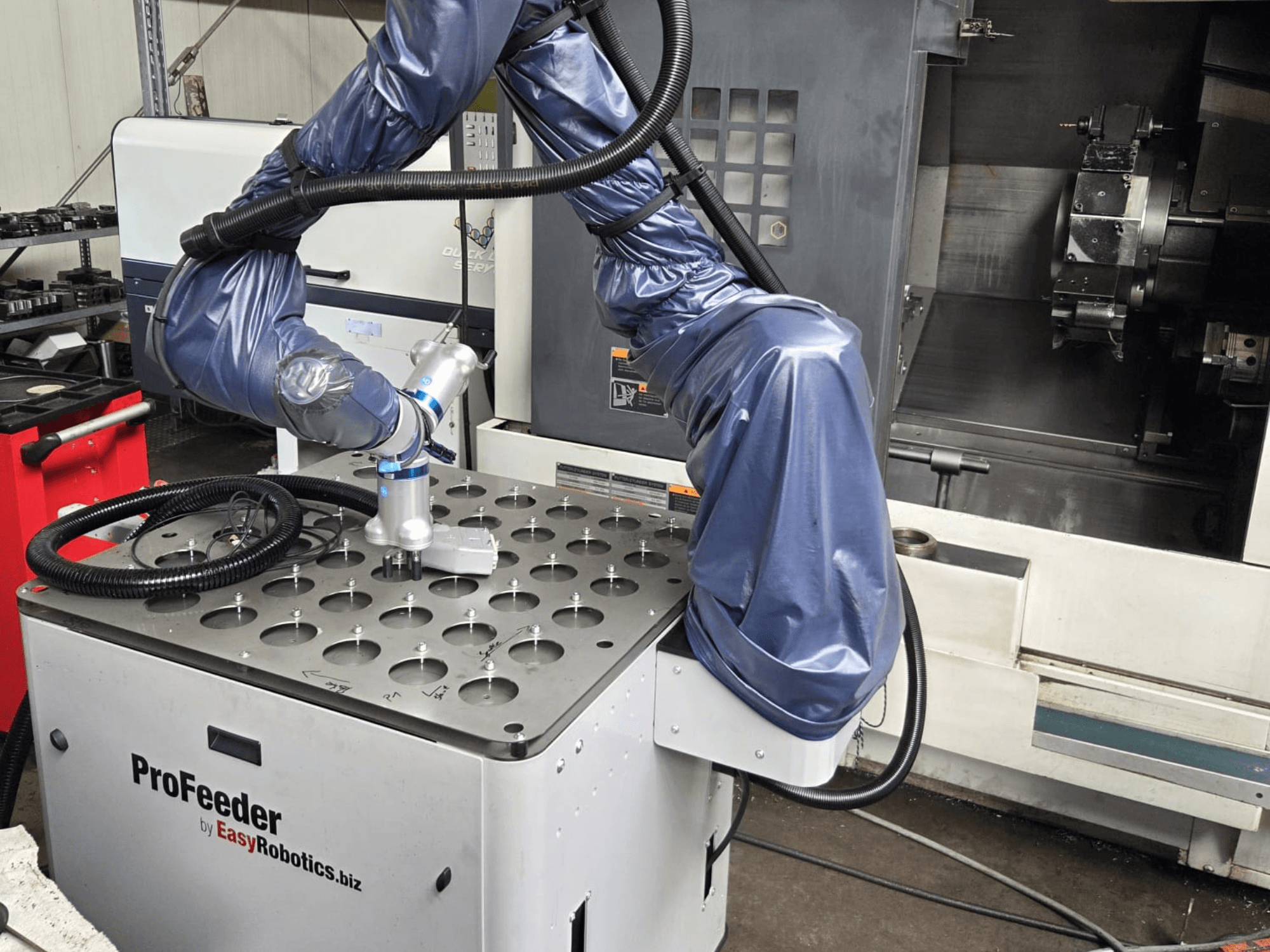 Колаборативний робот EASYROBOTICS ProFeeder спереду, з роботизованою рукою, розташованою над перфорованим металевим столом.