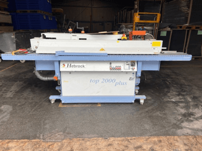 Hebrock Top 2000 Plus, вид спереду; промислова електрична машина з панеллю керування, колесами для мобільності та етикетками безпеки.
