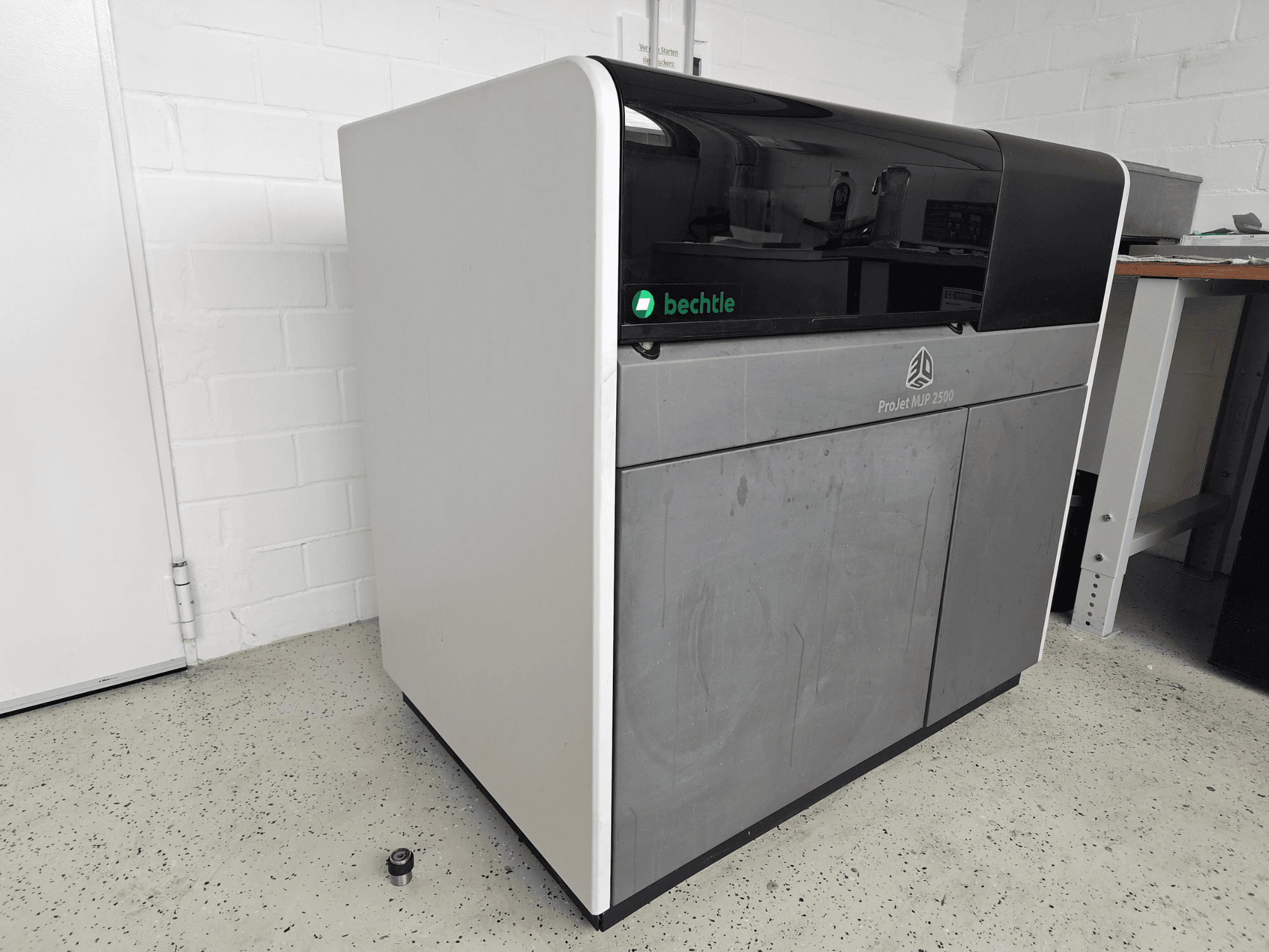 3D-принтер для друку з пластику 3D Systems ProJet MJP 2500 Plus у вигляд спереду; вирізняється елегантним дизайном із темною верхньою частиною та світлим корпусом.