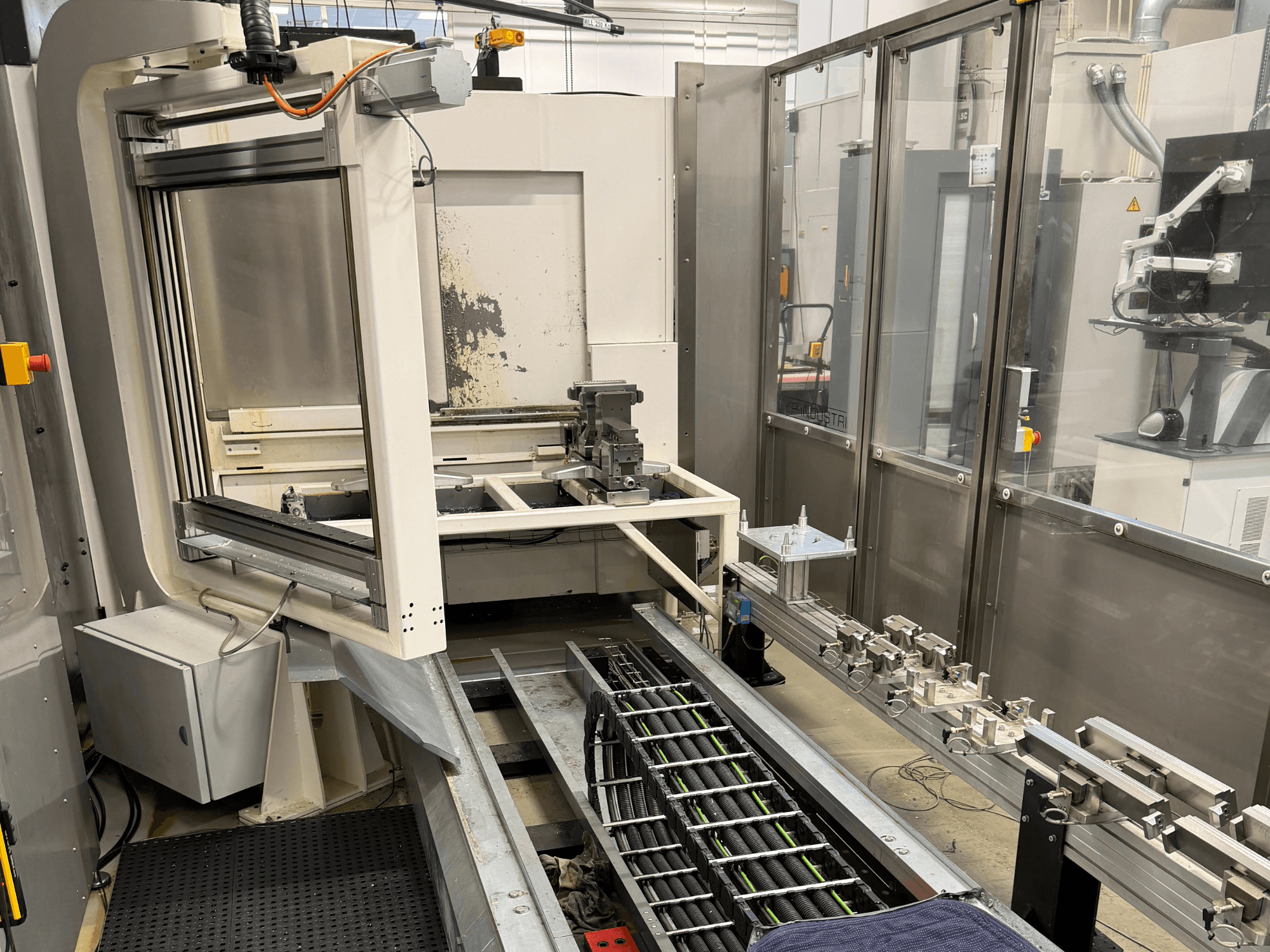 Автоматизоване промислове робоче місце, що демонструє роботизовану руку, рейкову систему та панель керування у вигляді збоку.