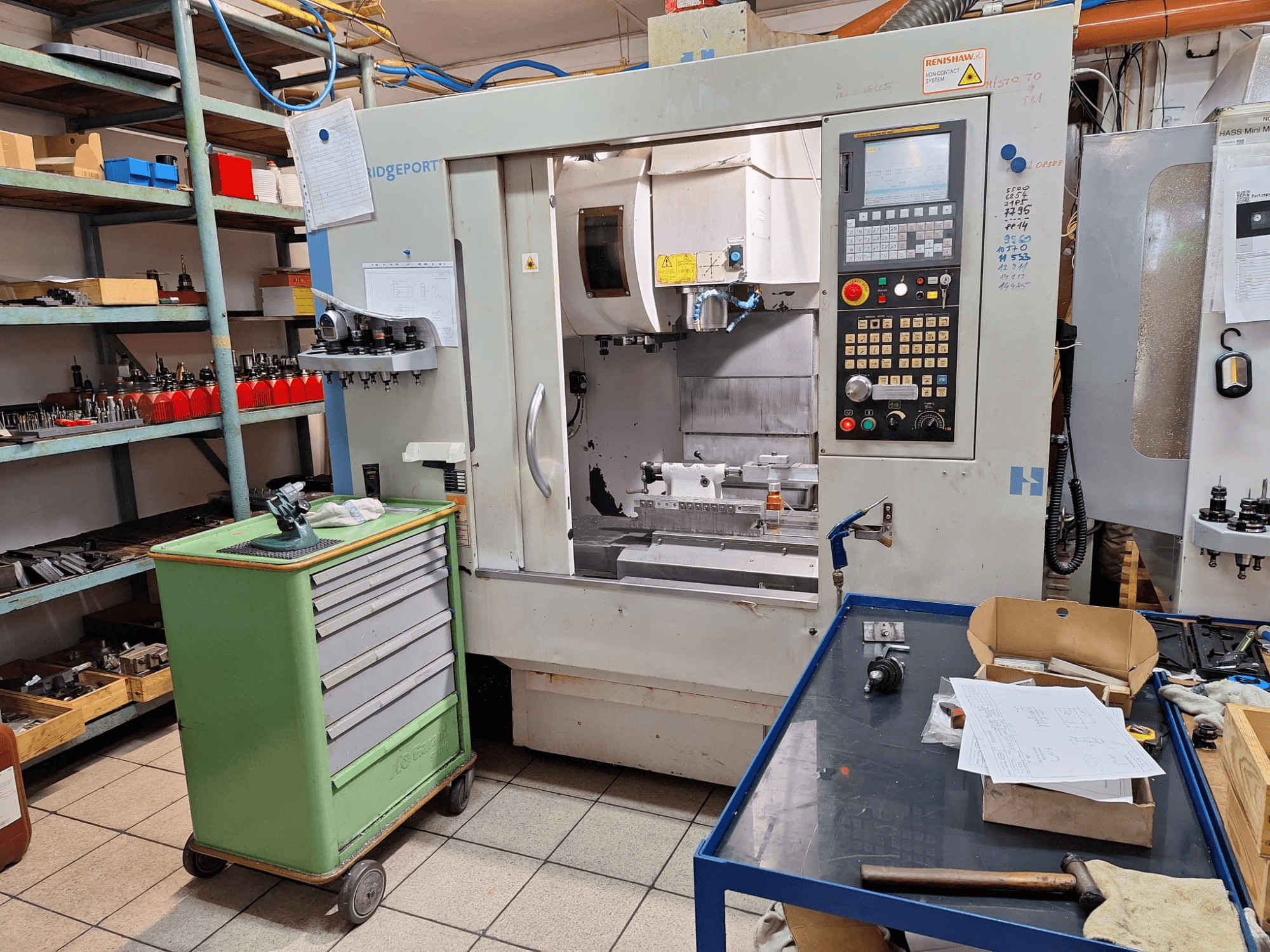 Вигляд спереду вертикального обробного центру Hardinge Bridgeport GX 710 з панеллю керування, інструментами та полицями в умовах цеху.