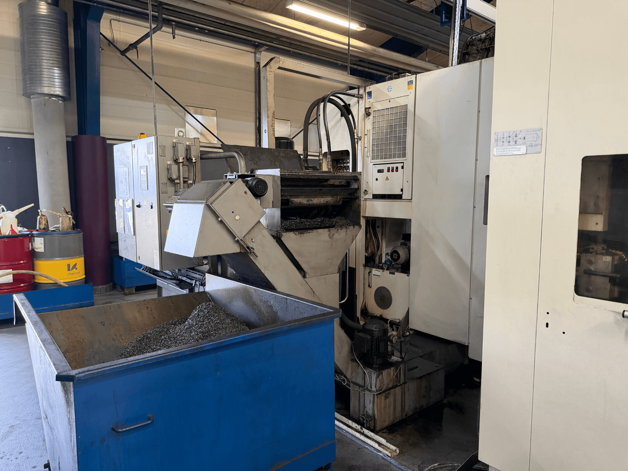 Вид спереду горизонтального обробного центру HELLER MCH 250 з контейнером для утилізації ЗОР і панеллю керування.