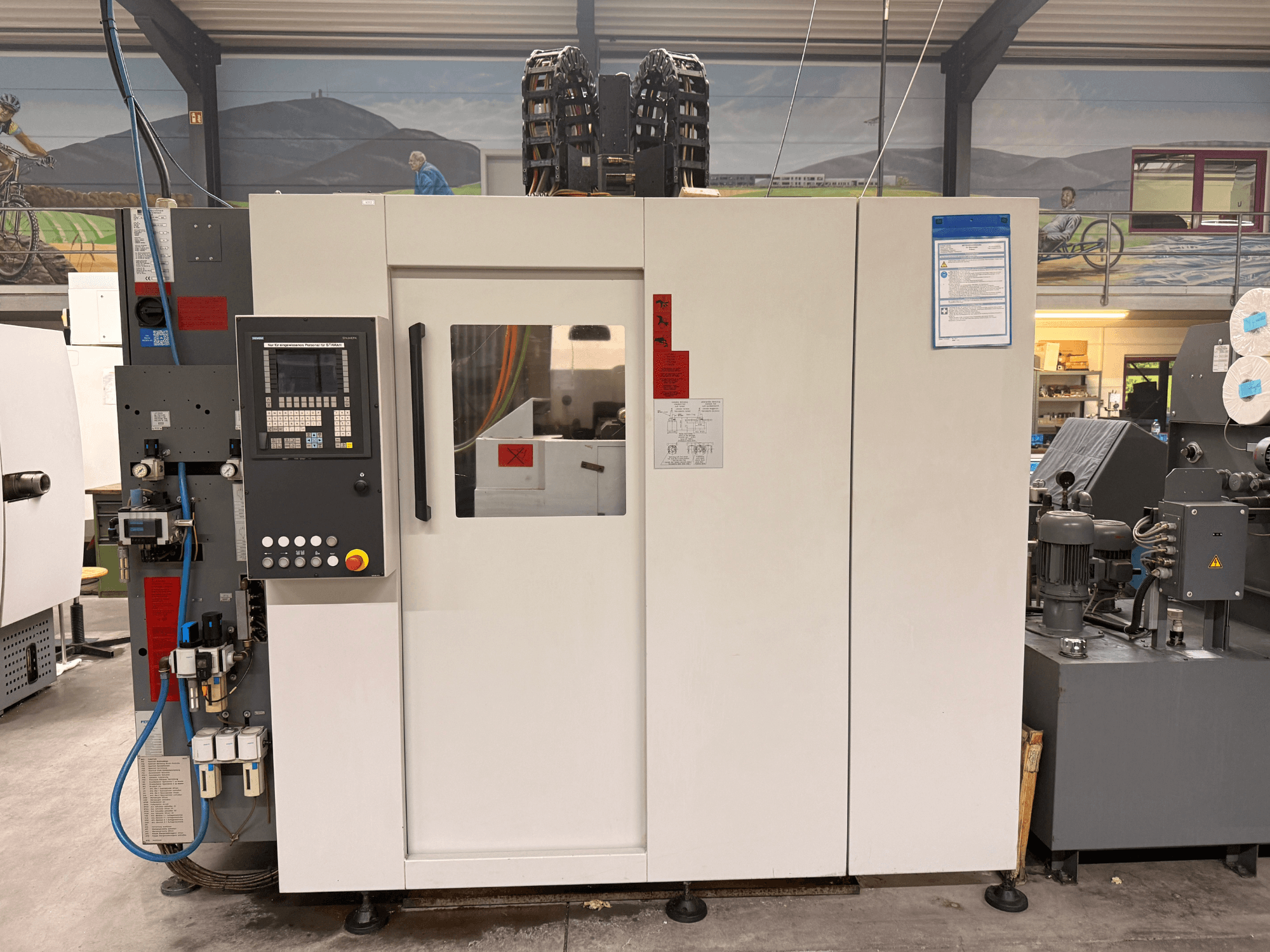 Білий обробний центр з ЧПК з панеллю керування, вигляд спереду, з кнопками та цифровим дисплеєм, в умовах майстерні.