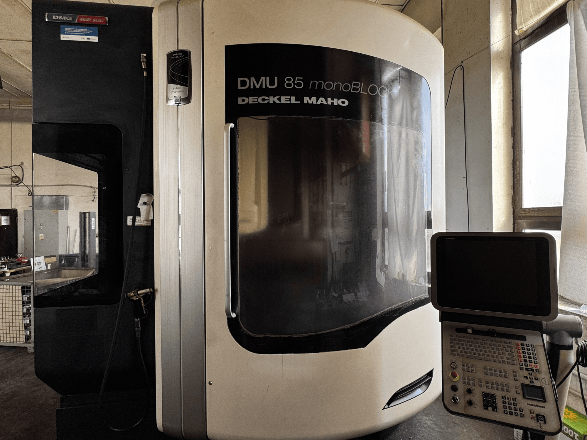 Вертикальний обробний центр DMG MORI DMU 85 monoBLOCK, вид спереду з панеллю керування та великим оглядовим вікном.