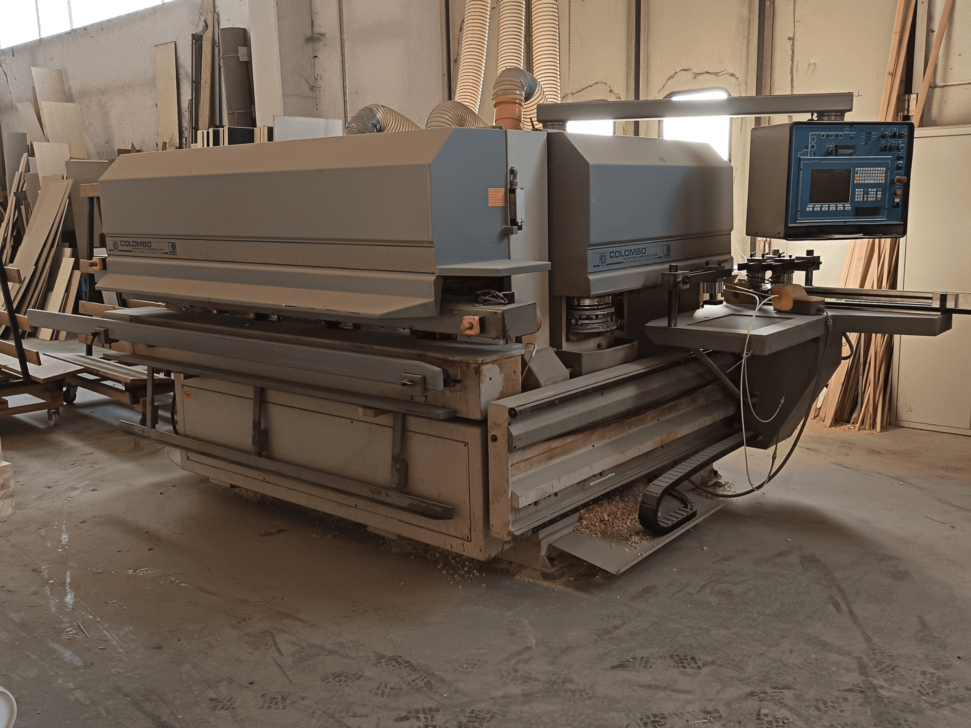 Деревообробний верстат Colombo, вид збоку, демонструє панель управління, ріжучі леза та скупчення пилу в майстерні.