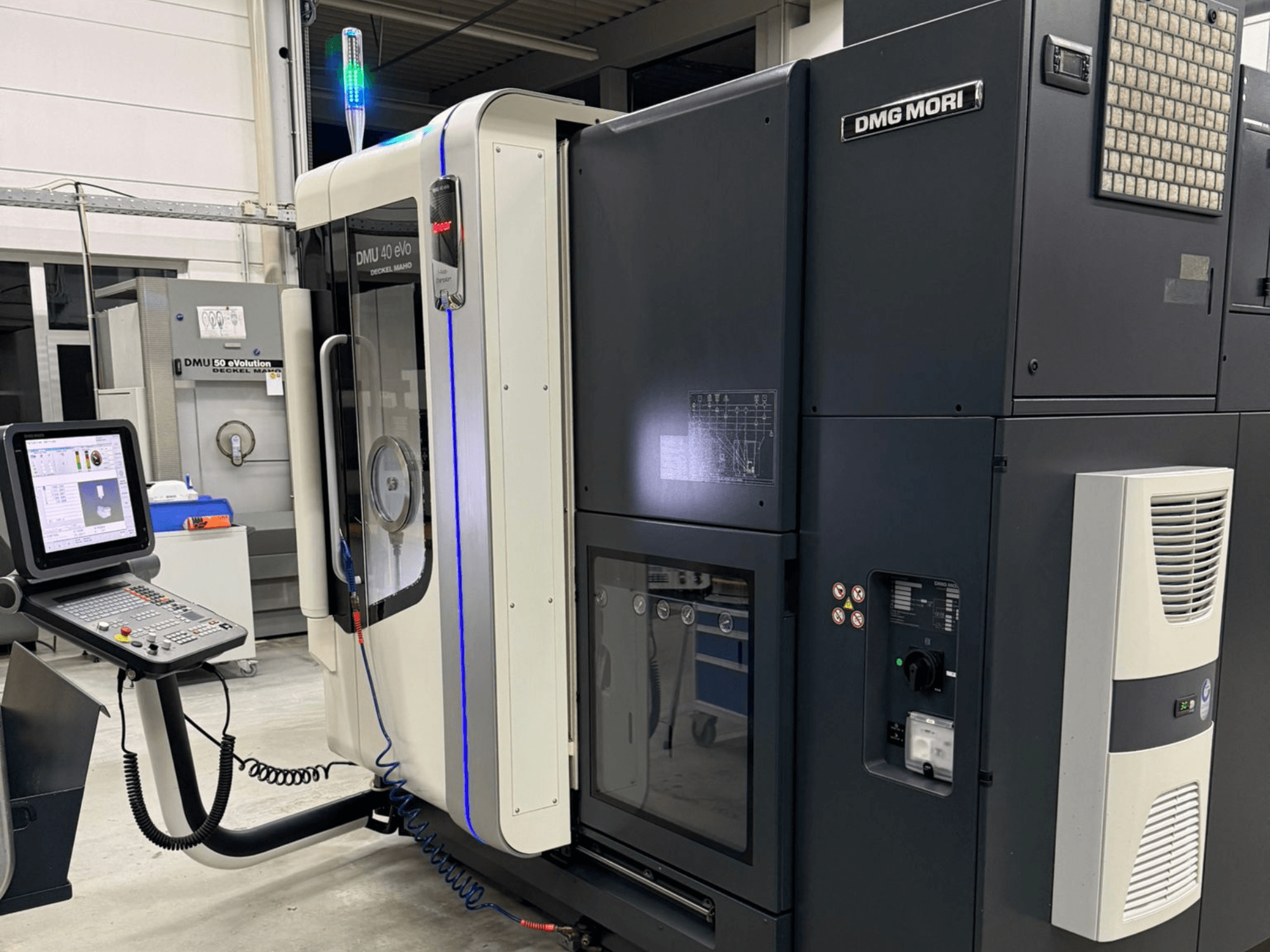 Машина DMG MORI DMU 40 eVo, вид спереду з елементами керування, світлодіодними індикаторами та витонченим дизайном, що підкреслює індустріальні характеристики.