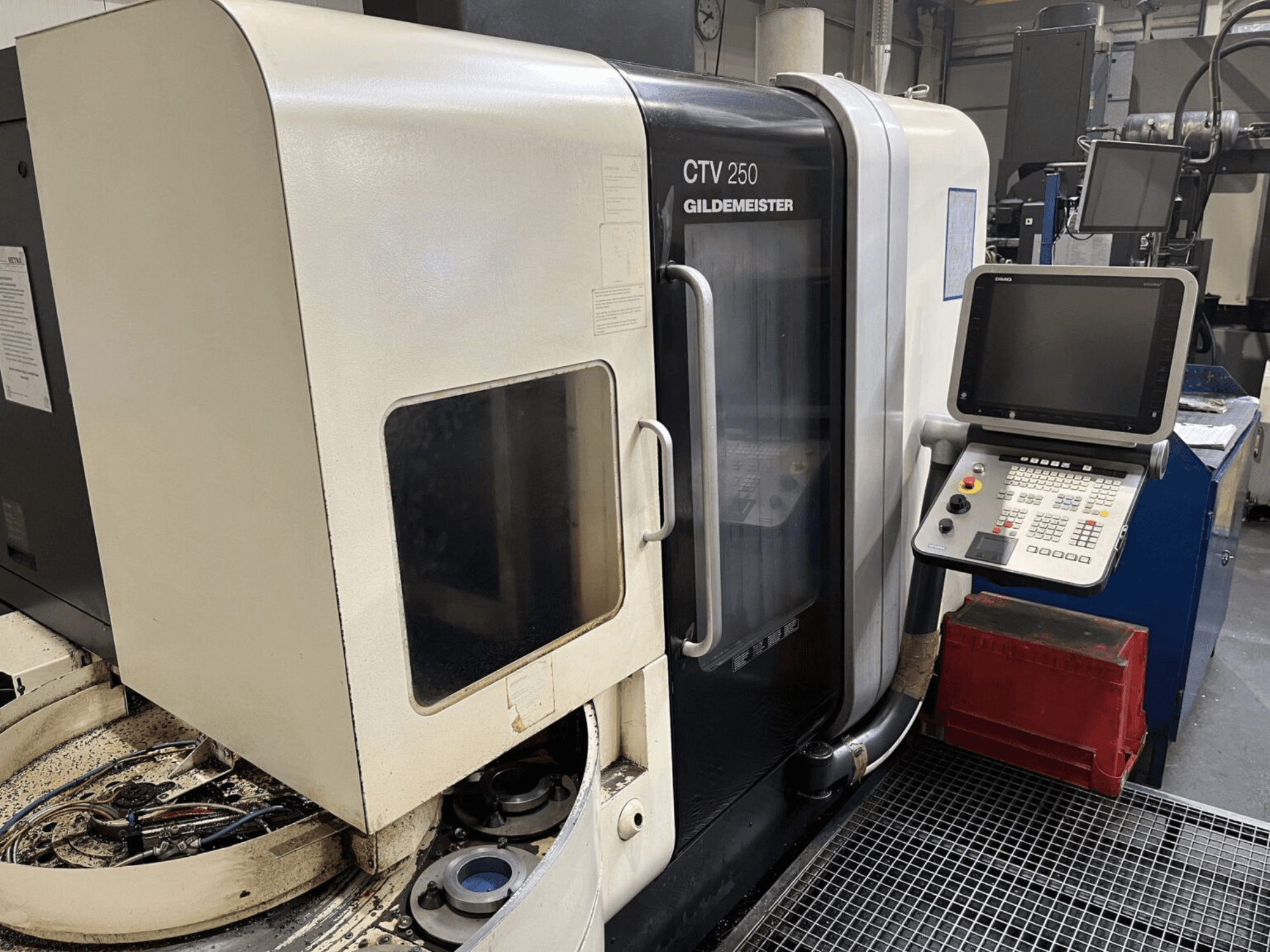 Вертикальний токарний верстат DMG CTV-250 вид спереду, демонструє панель управління і робочу зону з інструментами.