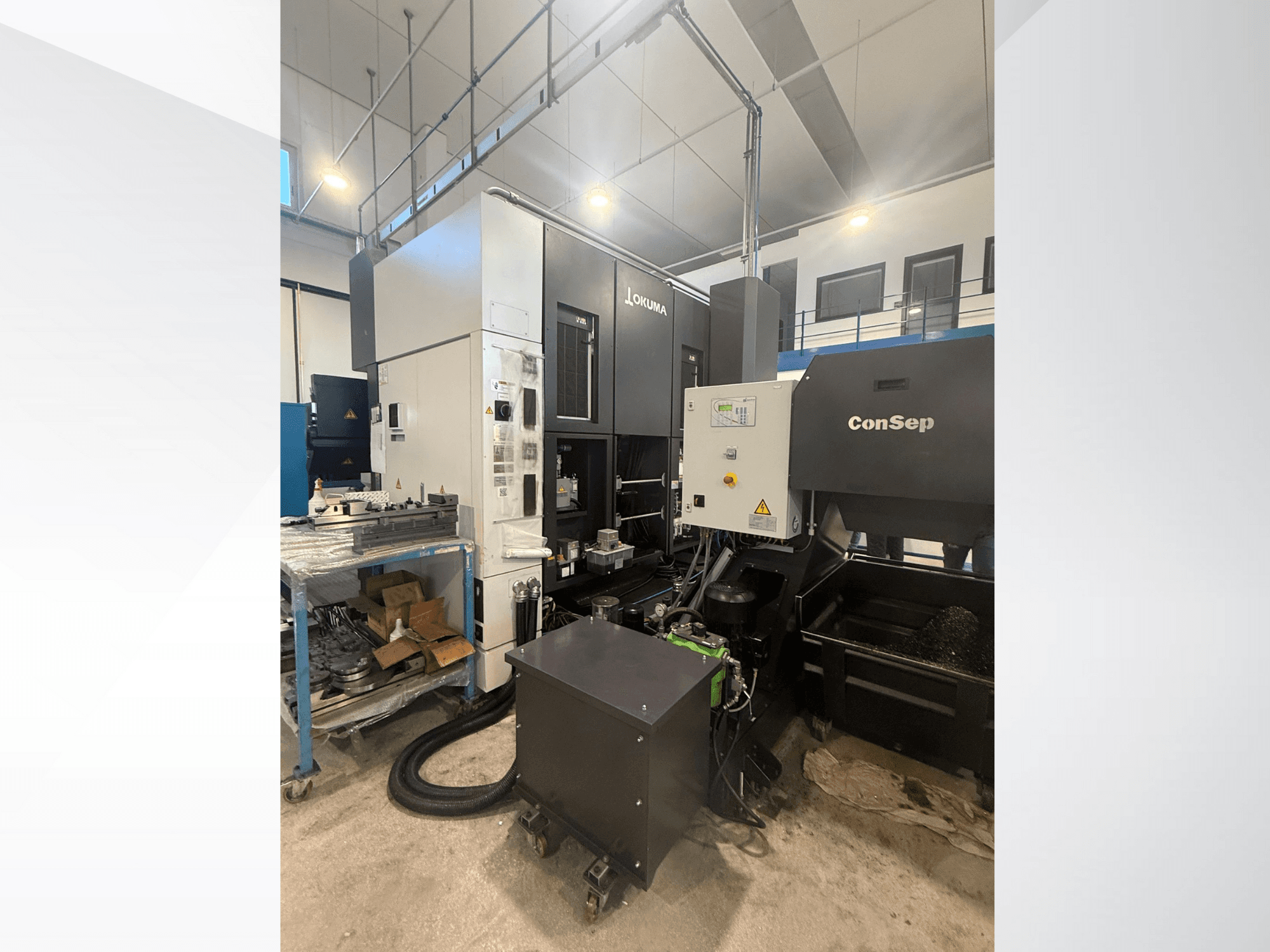 Обробний центр Okuma з блоком ConSep, вид збоку, елементи керування з дисплеєм і промисловим налаштуванням, включаючи контейнер для металевої стружки.