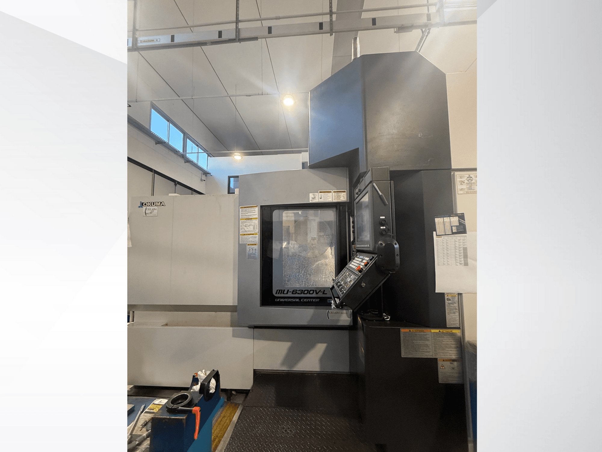 Верстат з ЧПК Okuma MU-6300V-L, вид спереду, з панеллю керування та етикетками безпеки.