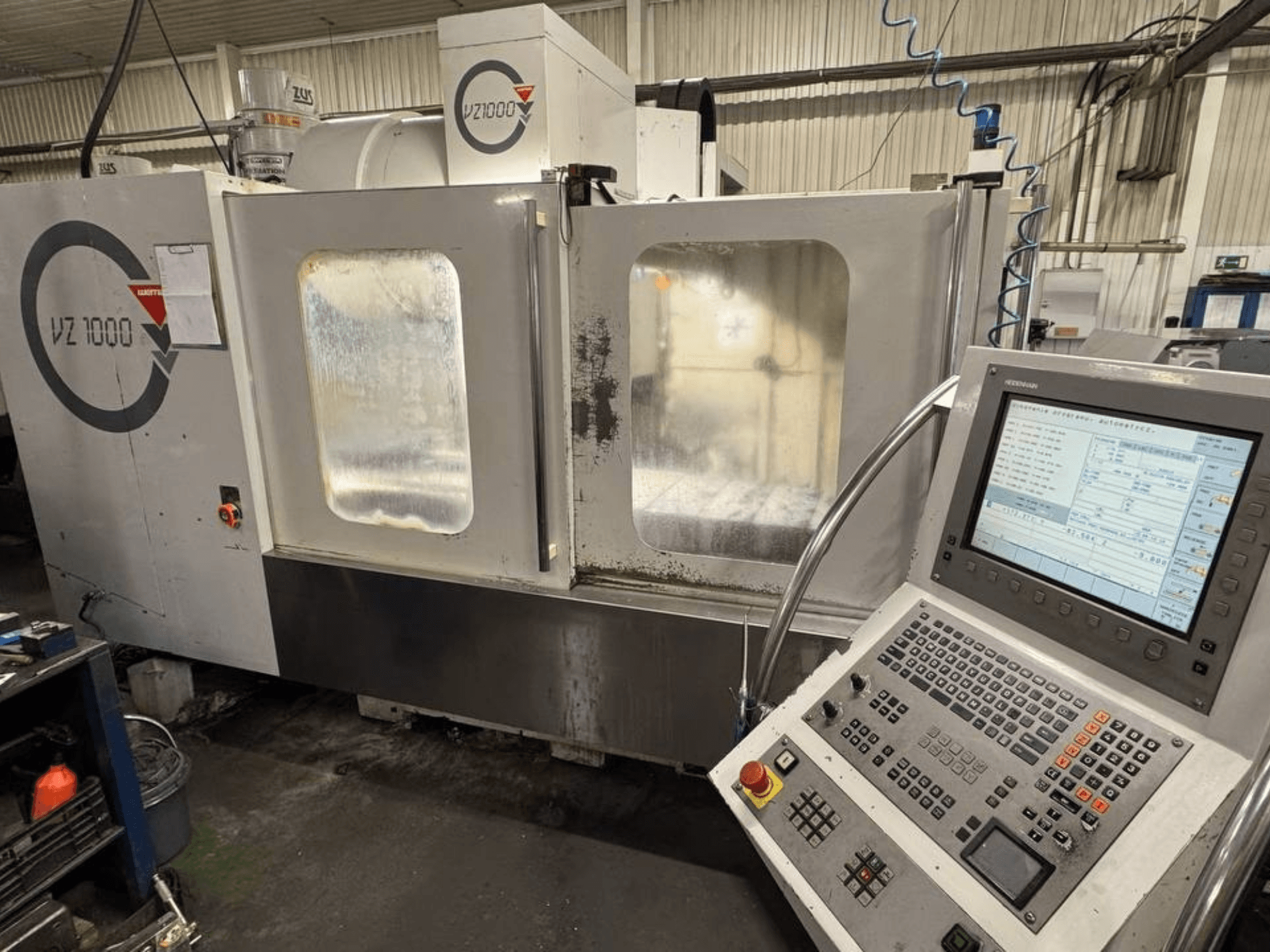 Вид спереду вертикального обробного центру WEMAS VZ 1000 з панеллю керування та прозорими дверцятами доступу.