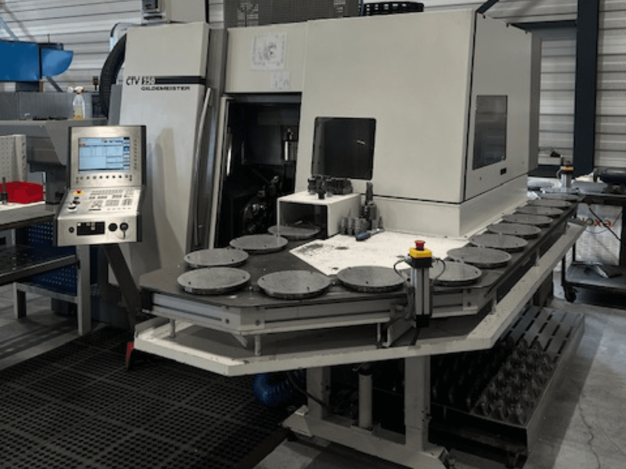 Інший текст: Обробний центр CTV E33 Goldmeister в майстерні, вид спереду, з панеллю керування та кількома круглими робочими платформами.