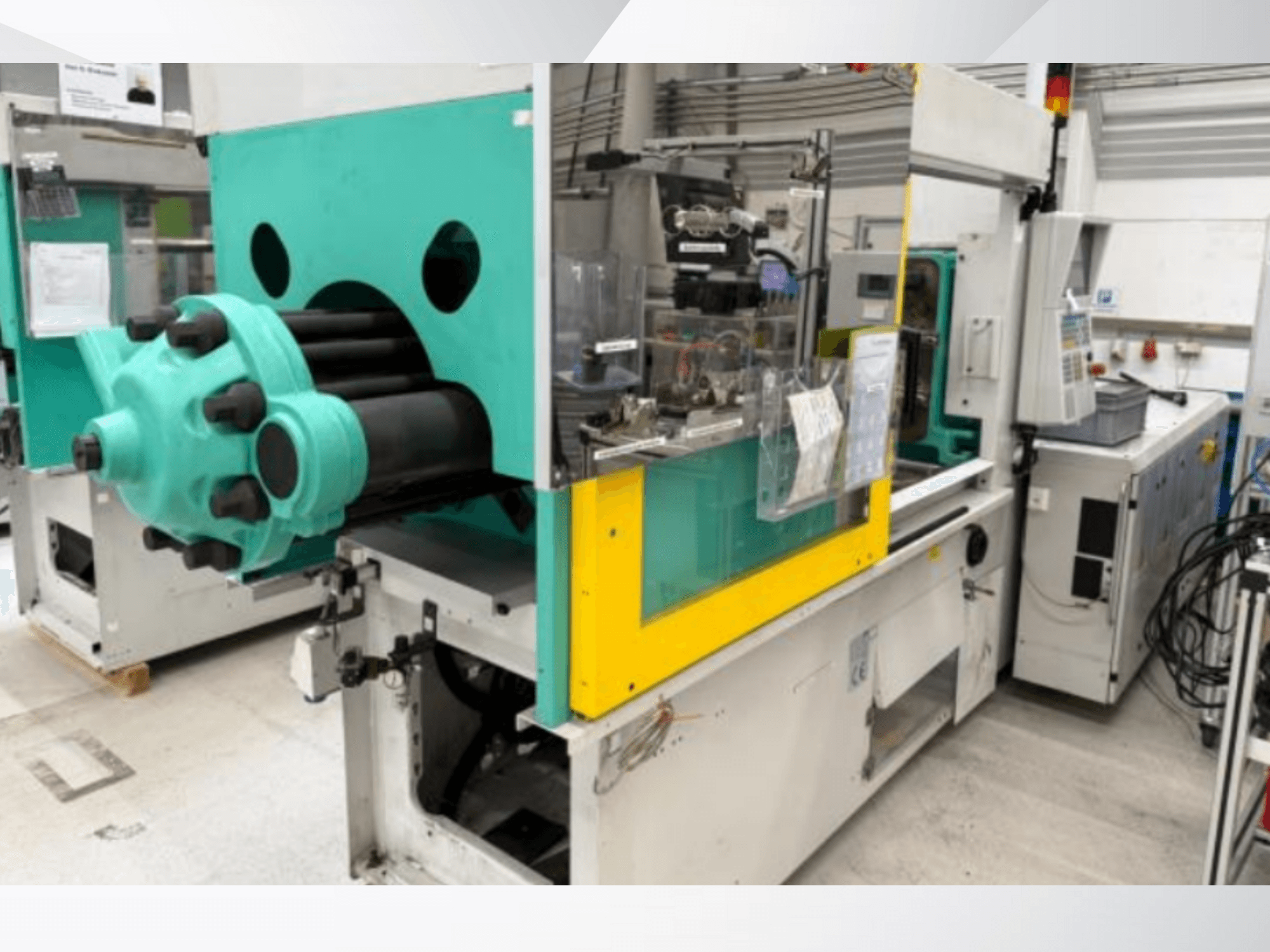 Машина для лиття під тиском, блакитно-жовтого кольору, вигляд спереду, з видимою прес-формою та панеллю керування з етикетками.