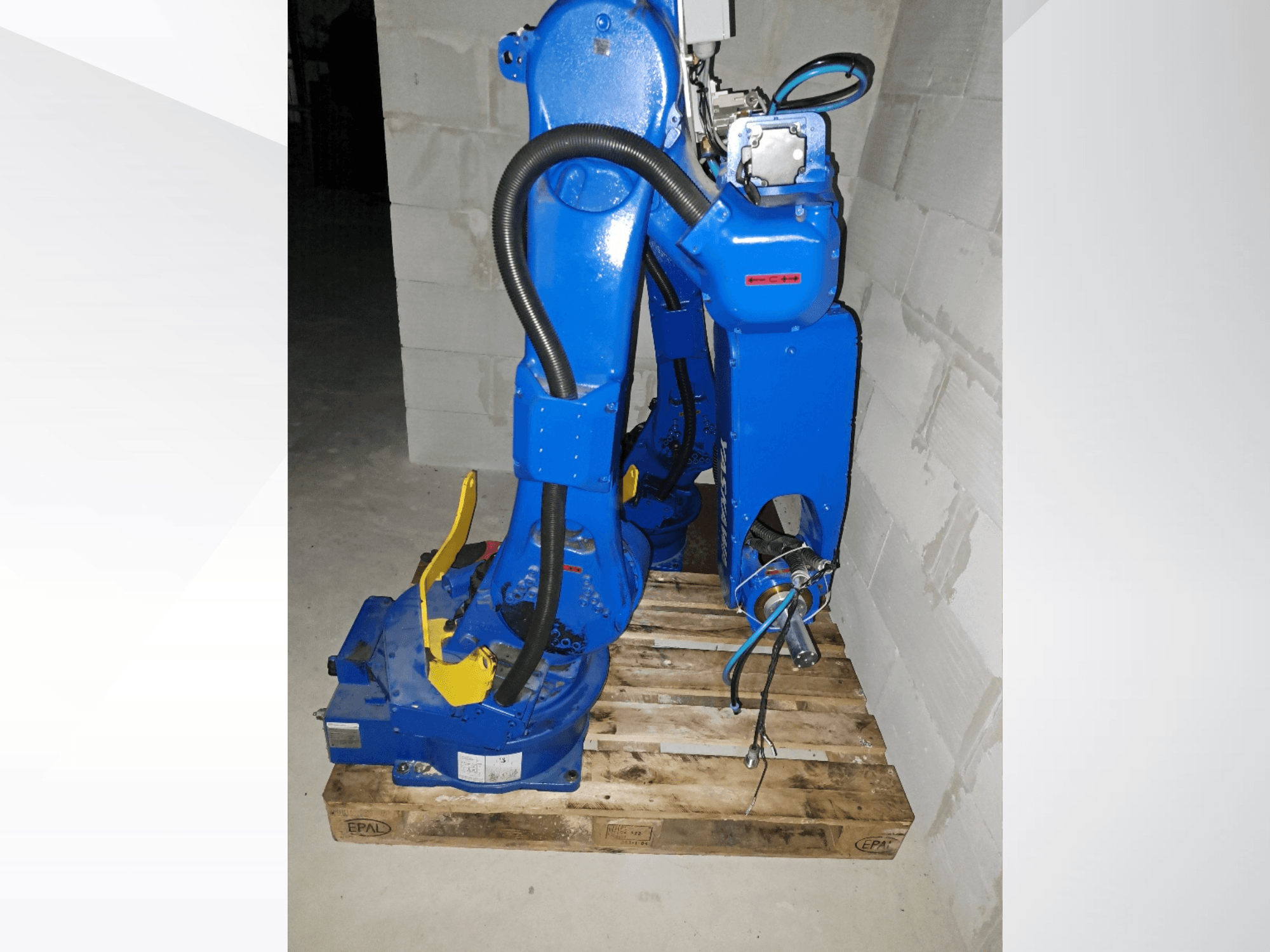 Роботизована рука Yaskawa Motoman GP25 синього кольору, вид збоку на дерев'яному піддоні, з кабелями та механічними з'єднаннями.