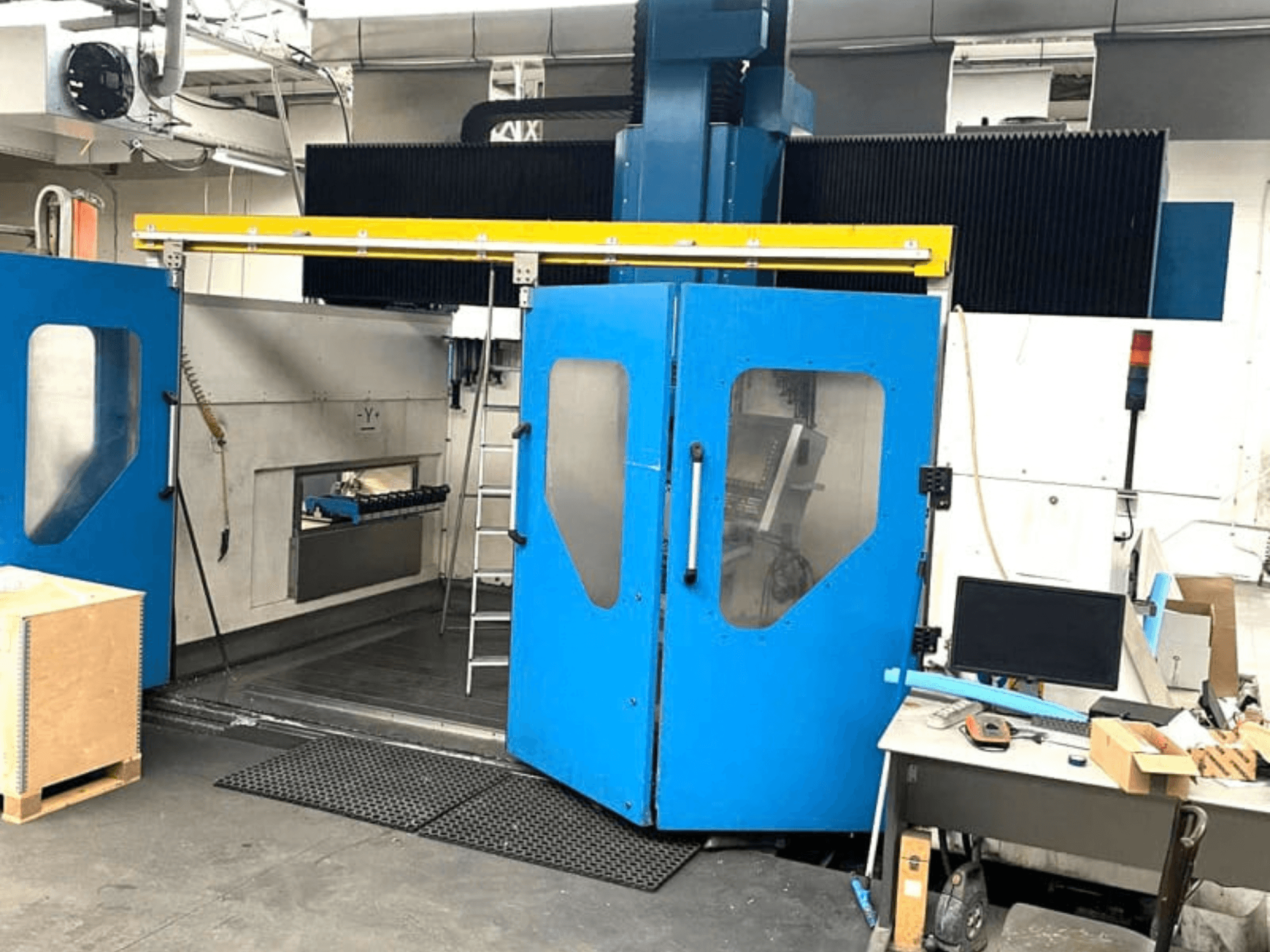 Вигляд спереду вертикального обробного центру TECHMILL LABOR SHAPE 3220 із відкритими синіми дверцятами, що відкривають огляд робочої зони всередині.