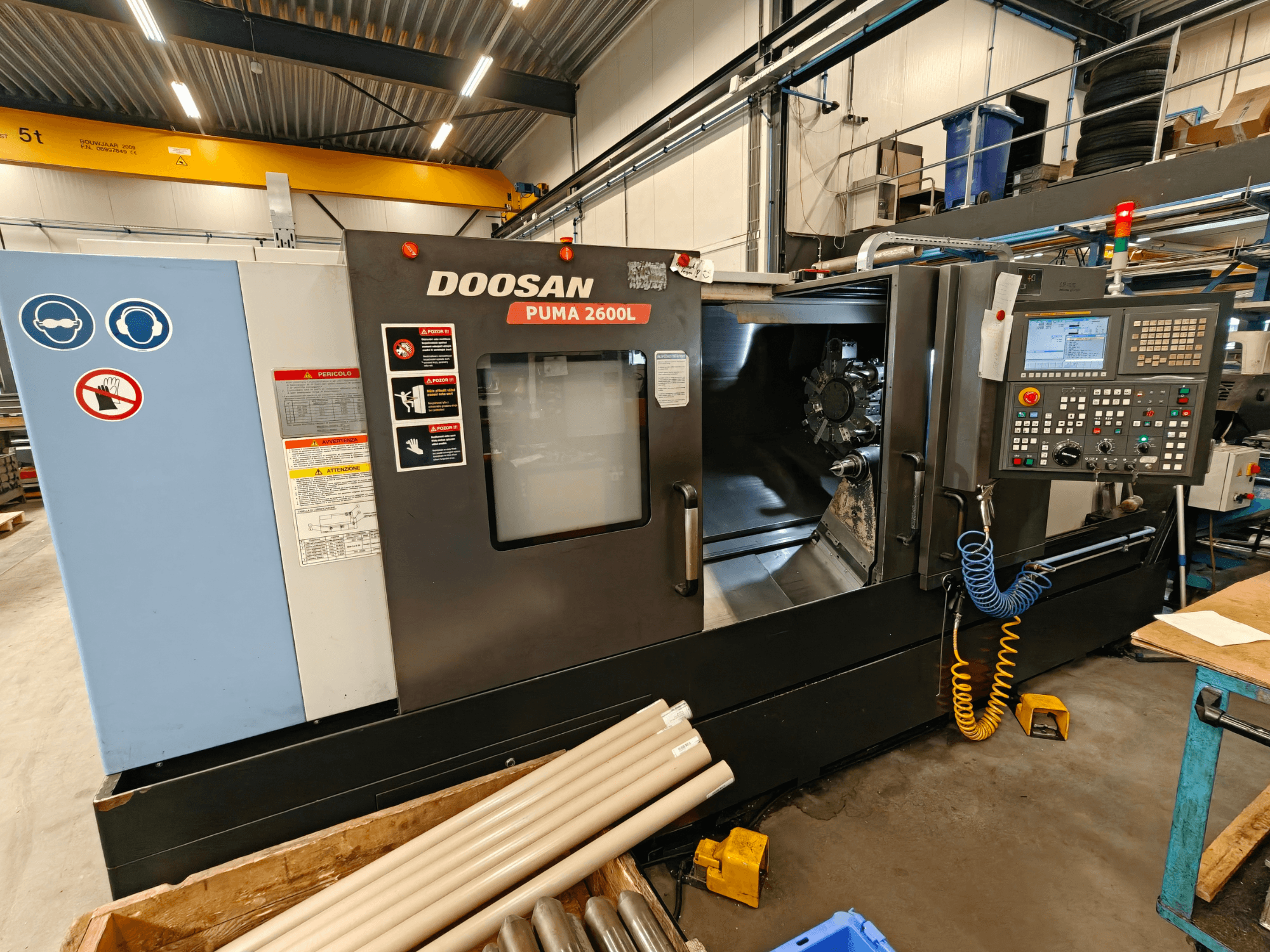 Горизонтальний токарний верстат DOOSAN Puma 2600L в майстерні, вид збоку: панель керування та зона шпинделя.
