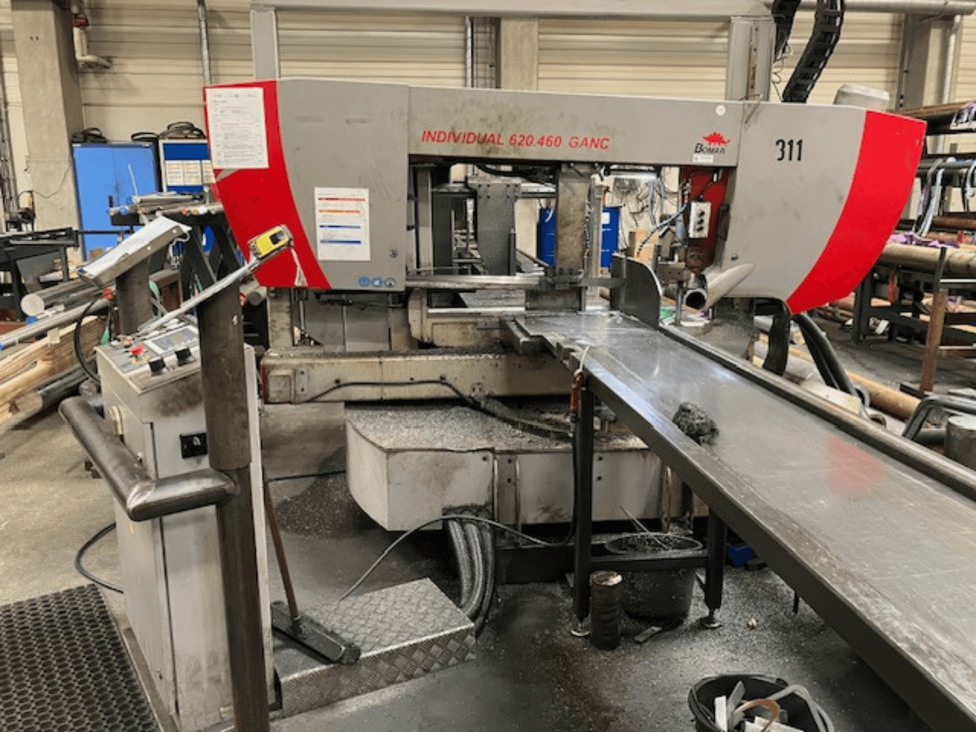 Стрічкова пила BOMAR INDIVIDIAL 620-460 GANC, вид спереду, з елементами керування, зоною різання та фоном промислового цеху.
