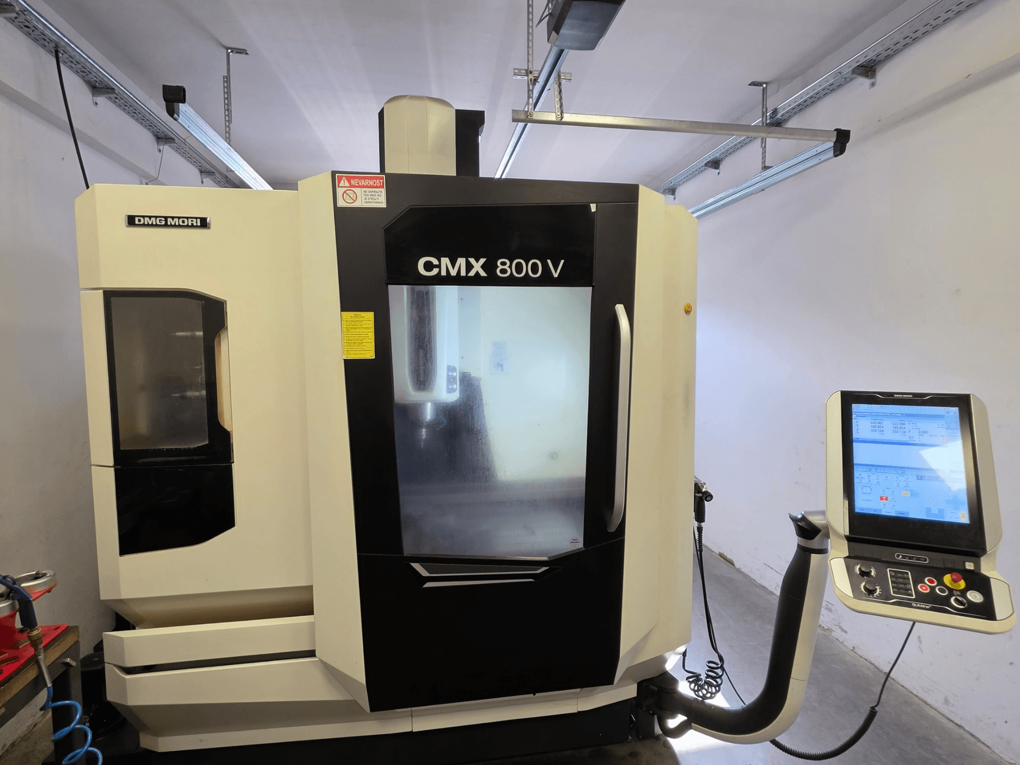 Вертикальний обробний центр DMG MORI CMX 800V, вид спереду, з сенсорною панеллю керування та чіткими знаками безпеки.