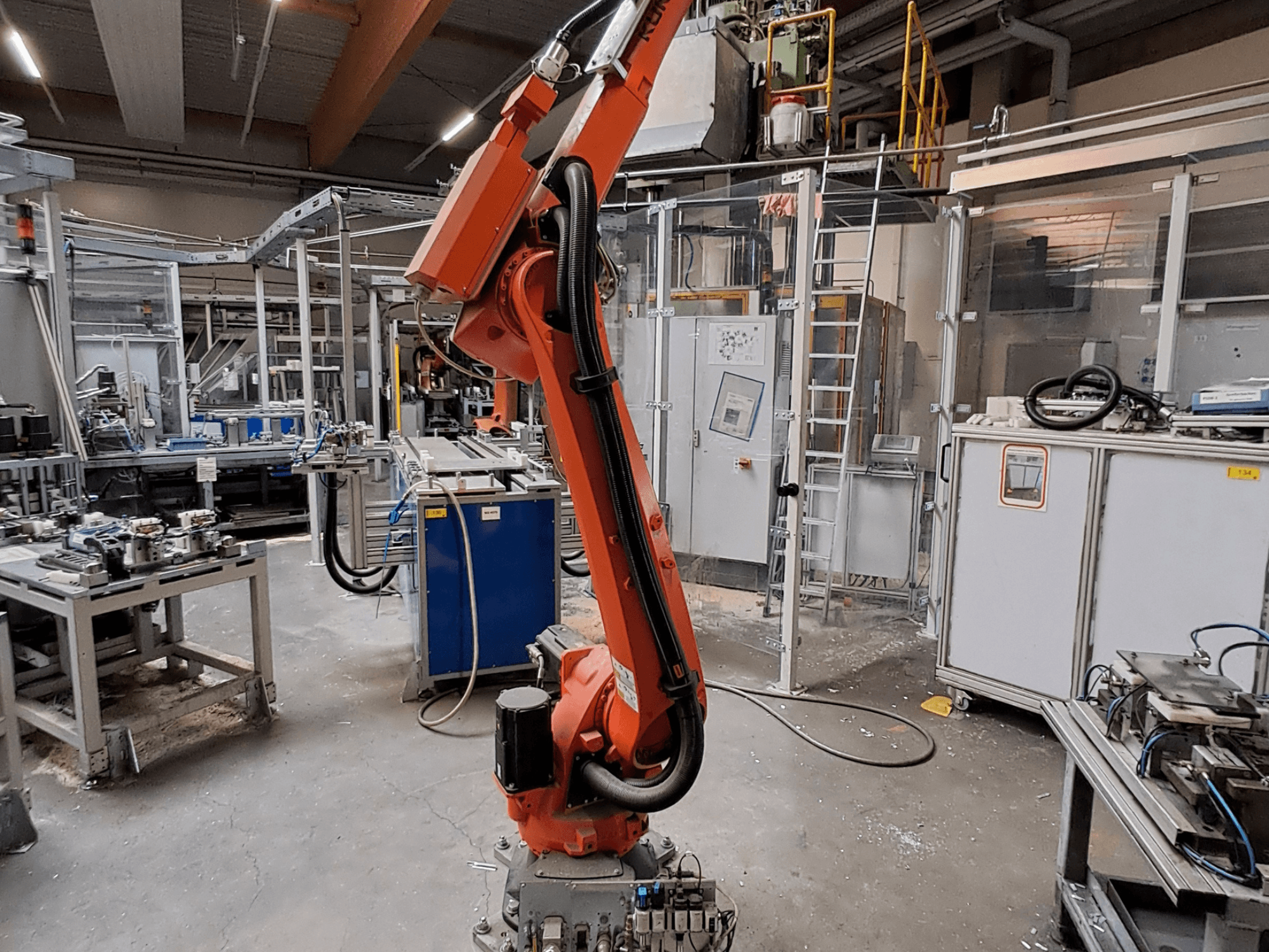 Роботизована рука KUKA KR 26 R3100/SEL у промисловому середовищі, зображена у боковому ракурсі на тлі виробничого обладнання.