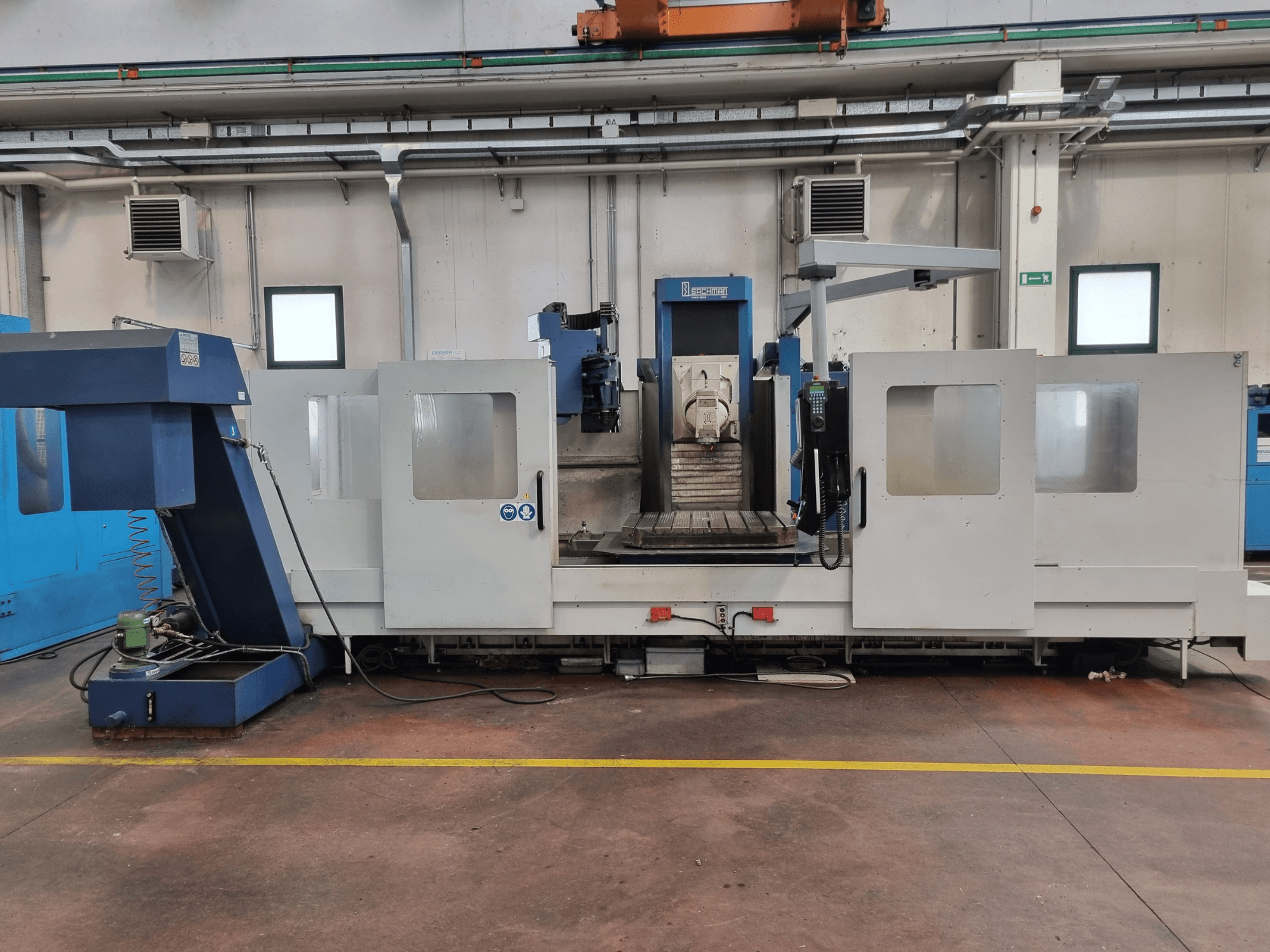 Фрезерний верстат з ЧПК фірми "Brembana", вид збоку, що показує панель управління та робочу зону з робочим столом всередині.