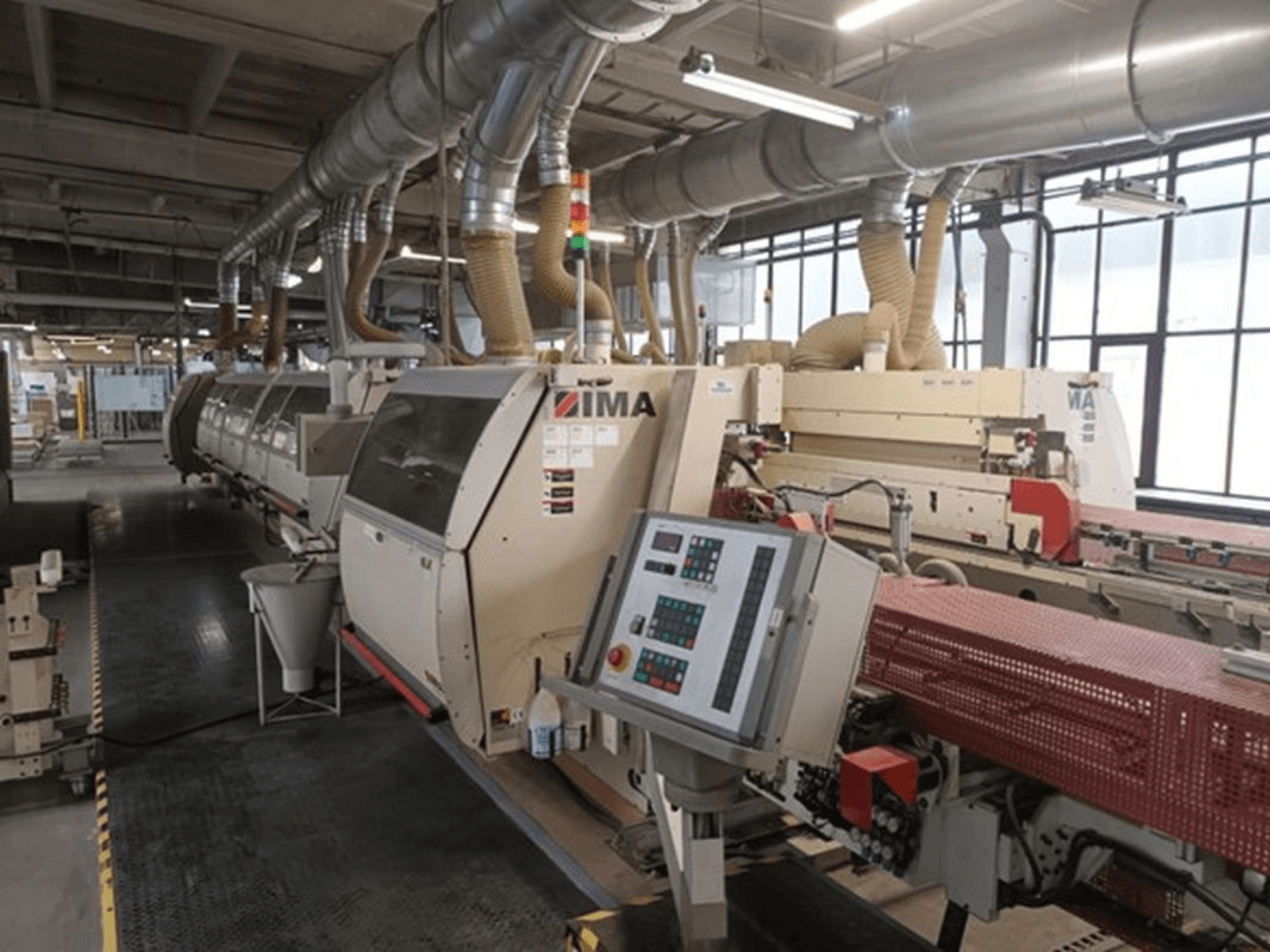 Промислове обладнання IMA у заводських умовах, вид спереду, з панелями керування та трубами для відсмоктування пилу.