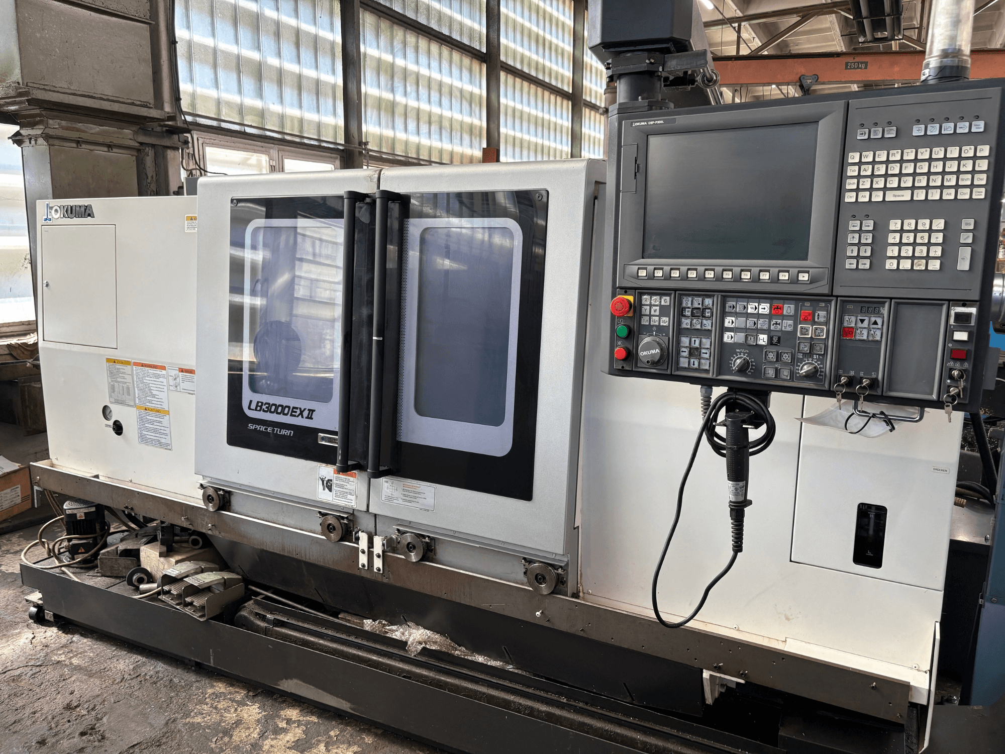 Горизонтальний токарний верстат Okuma LB3000EXII, вид спереду, на якому видно панель управління та завантажувальні дверцята.