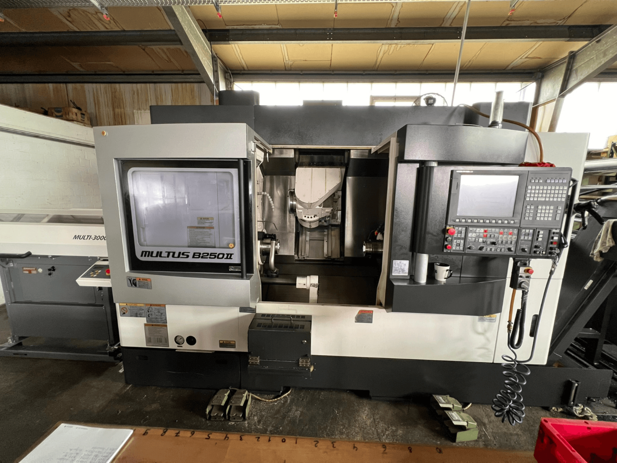 Токарно-фрезерний центр Okuma Multus B250II MW, вид спереду, на якому видно деталі панелі керування та зони обробки.