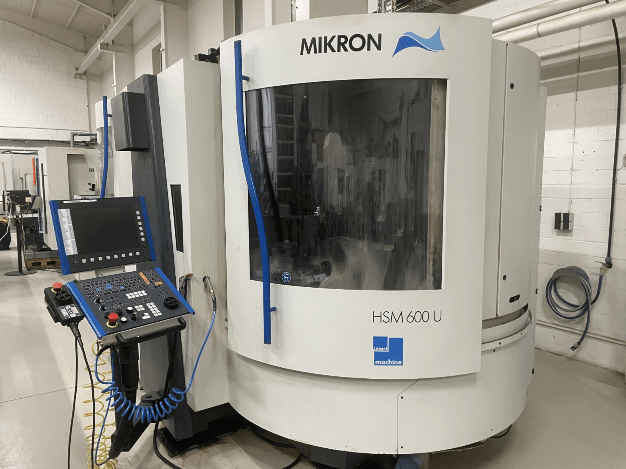 Вертикальний обробний центр MIKRON HSM600U показаний спереду, з панеллю керування та великим оглядовим вікном.