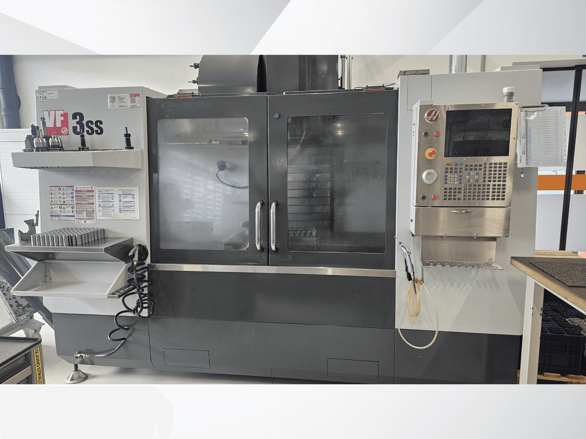 Вертикальний обробний центр HAAS VF-3SS, вид спереду, з панеллю керування, стелажем для інструментів та великими скляними дверцятами.
