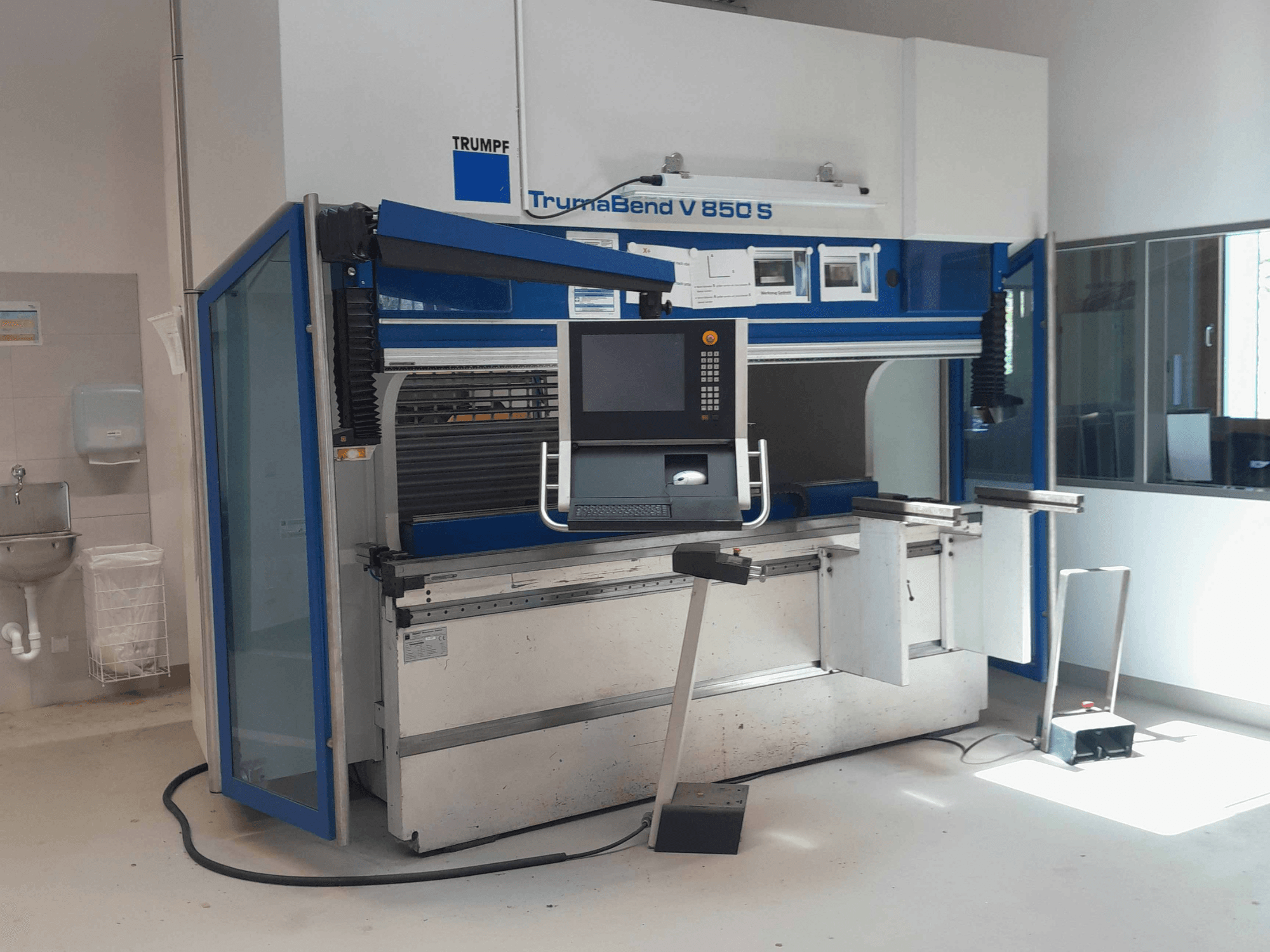 Гнучкий прес TRUMPF TrumaBend V 850 S, вид спереду з панеллю керування та засобами безпеки у світлому робочому приміщенні.
