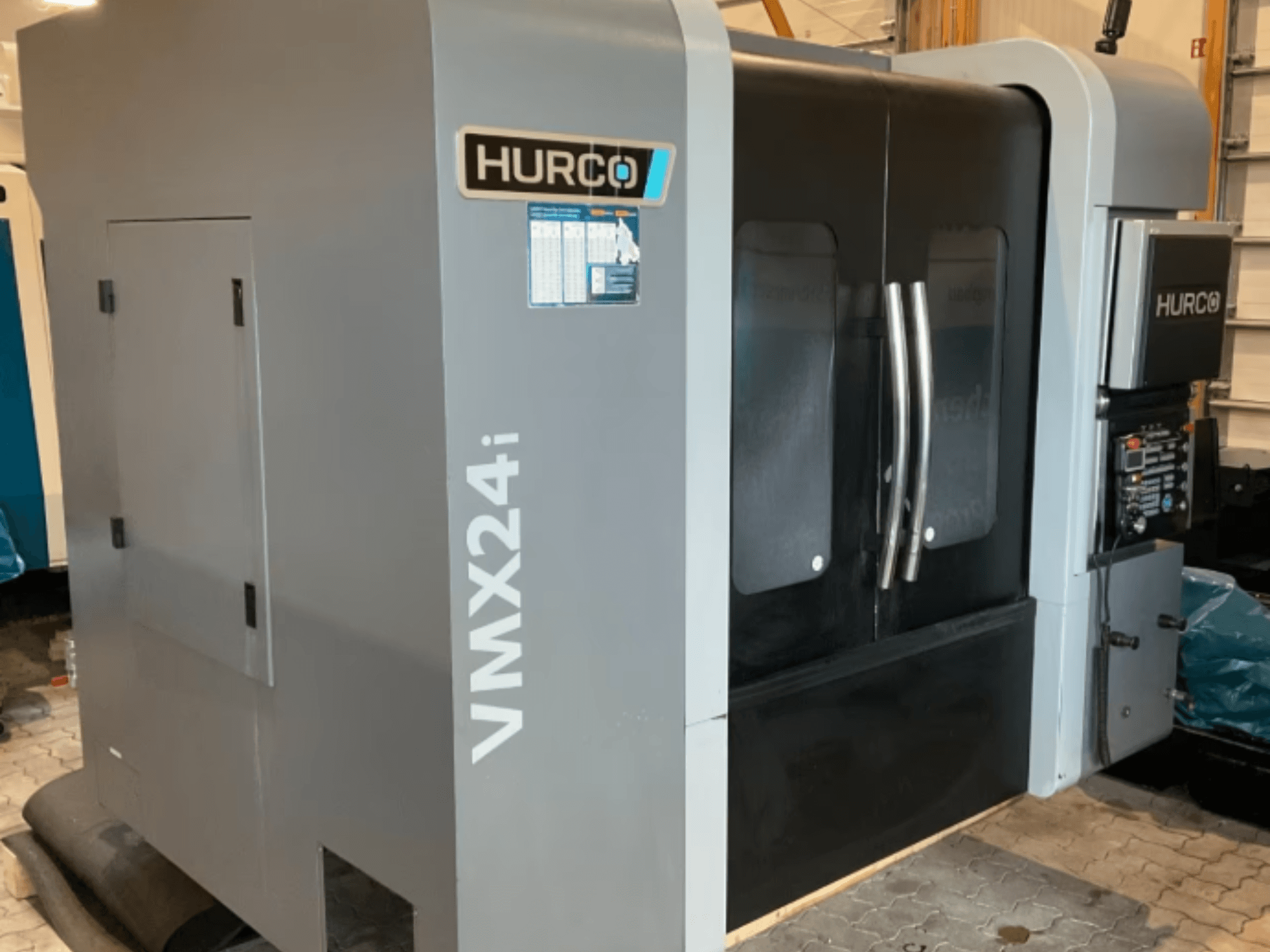 Вертикальний обробний центр Hurco VMX 24i, вид спереду: корпус металічного сірого кольору, чорні дверцята панелей та інтерфейс управління.