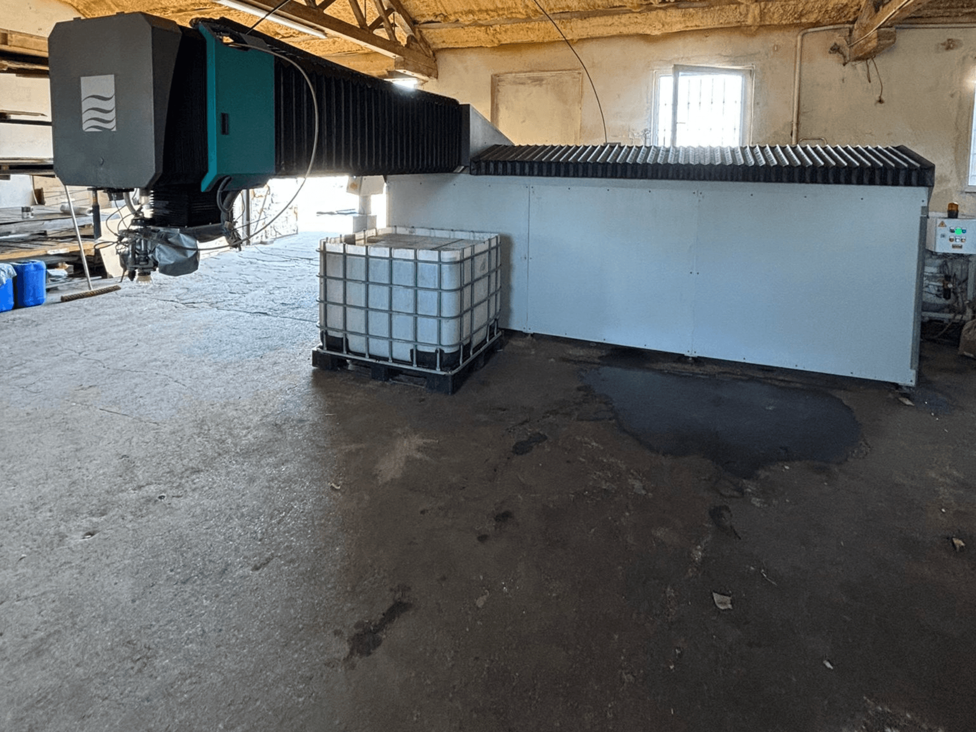 Промисловий водоструминний апарат у майстерні, вид збоку, з великим резервуаром для води та панеллю керування поруч.