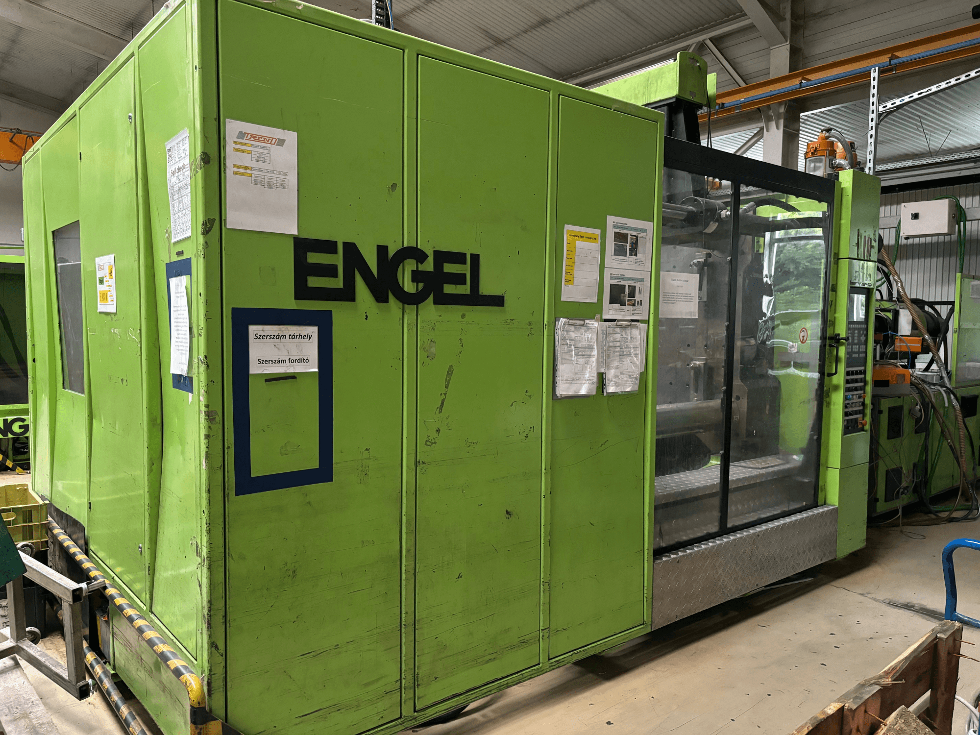 Гідравлічна машина для лиття під тиском Engel DUO 5550/800, вид спереду, із зеленим зовнішнім виглядом і прозорою панеллю доступу.