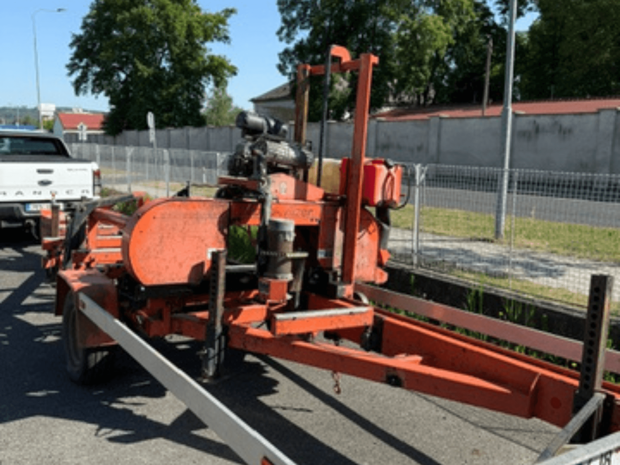 Стрічкова пила для деревини WOOD-MIZER LT40 оранжевого кольору, вид збоку на причепі з видимими колесами та деталями двигуна.