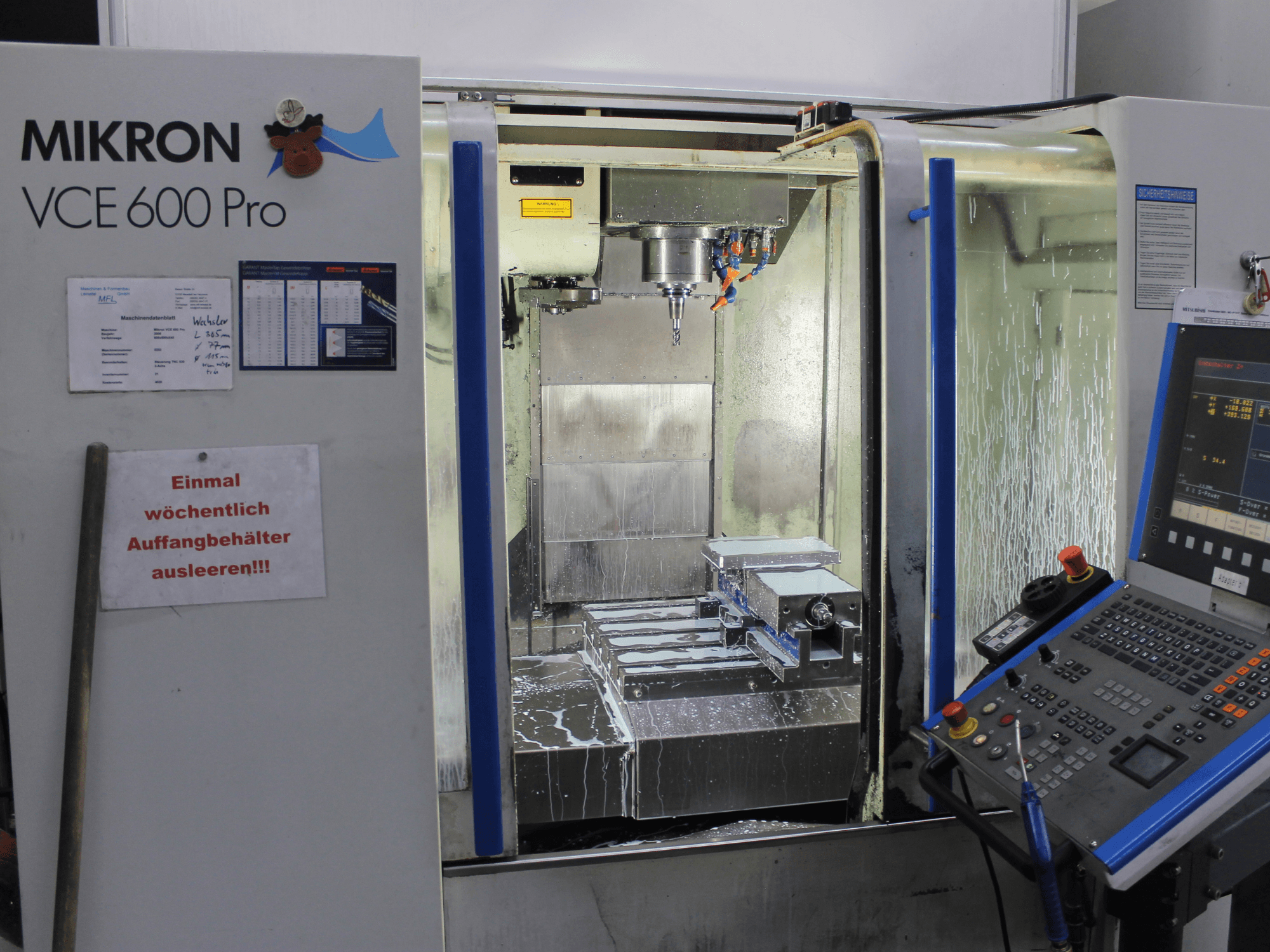 Обробний центр Mikron VCE 600 Pro, вид спереду, оснащений ріжучими інструментами, розпилювачем ЗОР і панеллю керування з кнопками.