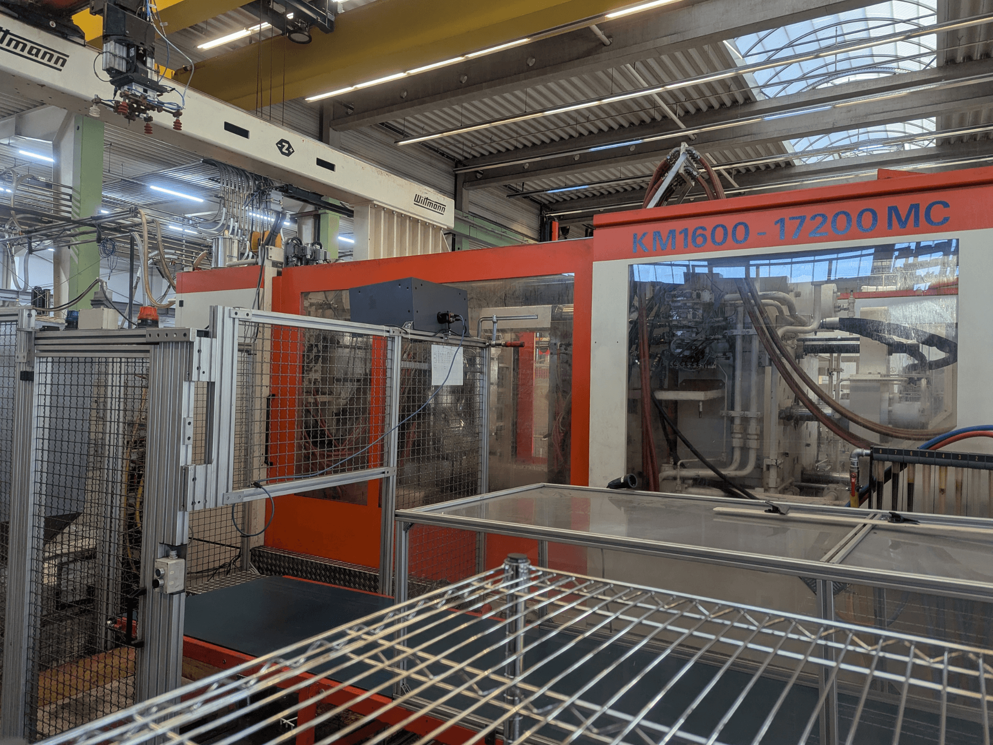 Гідравлічний термопластавтомат Krauss Maffei KM 1600-17200MC, вид спереду з видимою панеллю керування та гідравлічними лініями.