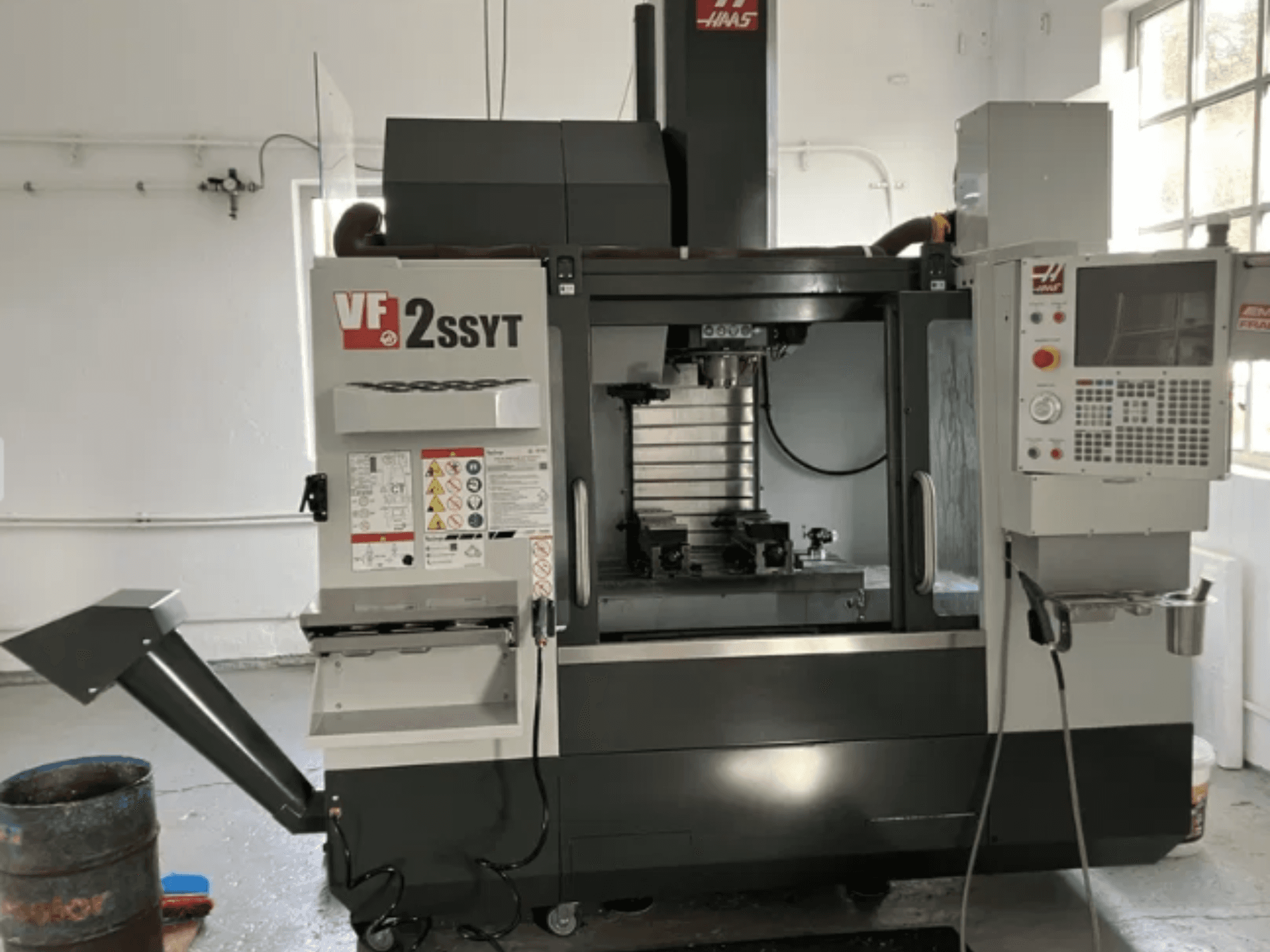 Фрезерний верстат з ЧПК Haas VF-2SSYT, вид спереду, з панеллю керування, тримачем інструменту та системою охолодження для обробки металу.