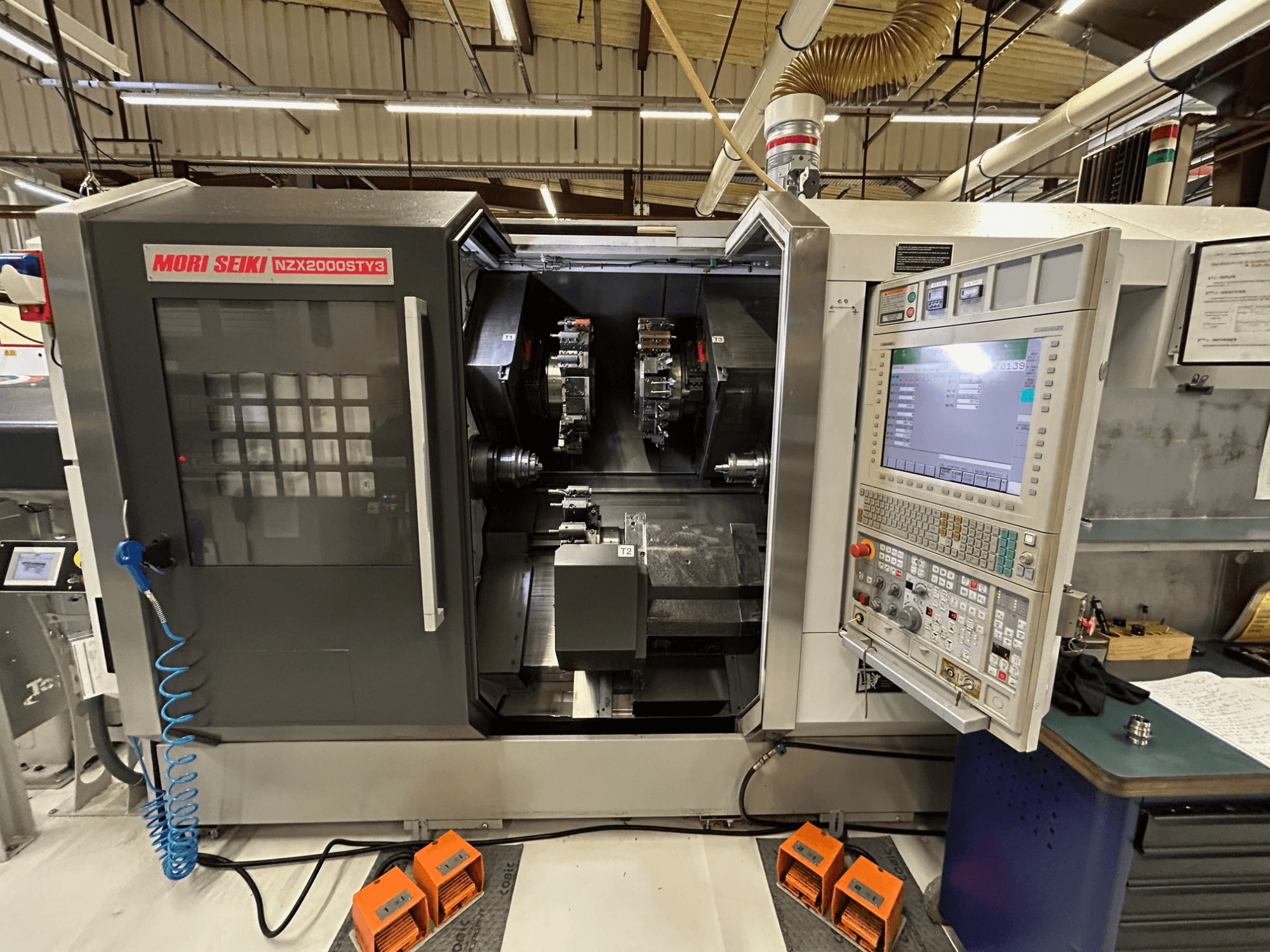 Багатошпиндельний токарний верстат MORI SEIKI NZ2000 ST3Y3, вид спереду, на якому видно панель управління та зону обробки.