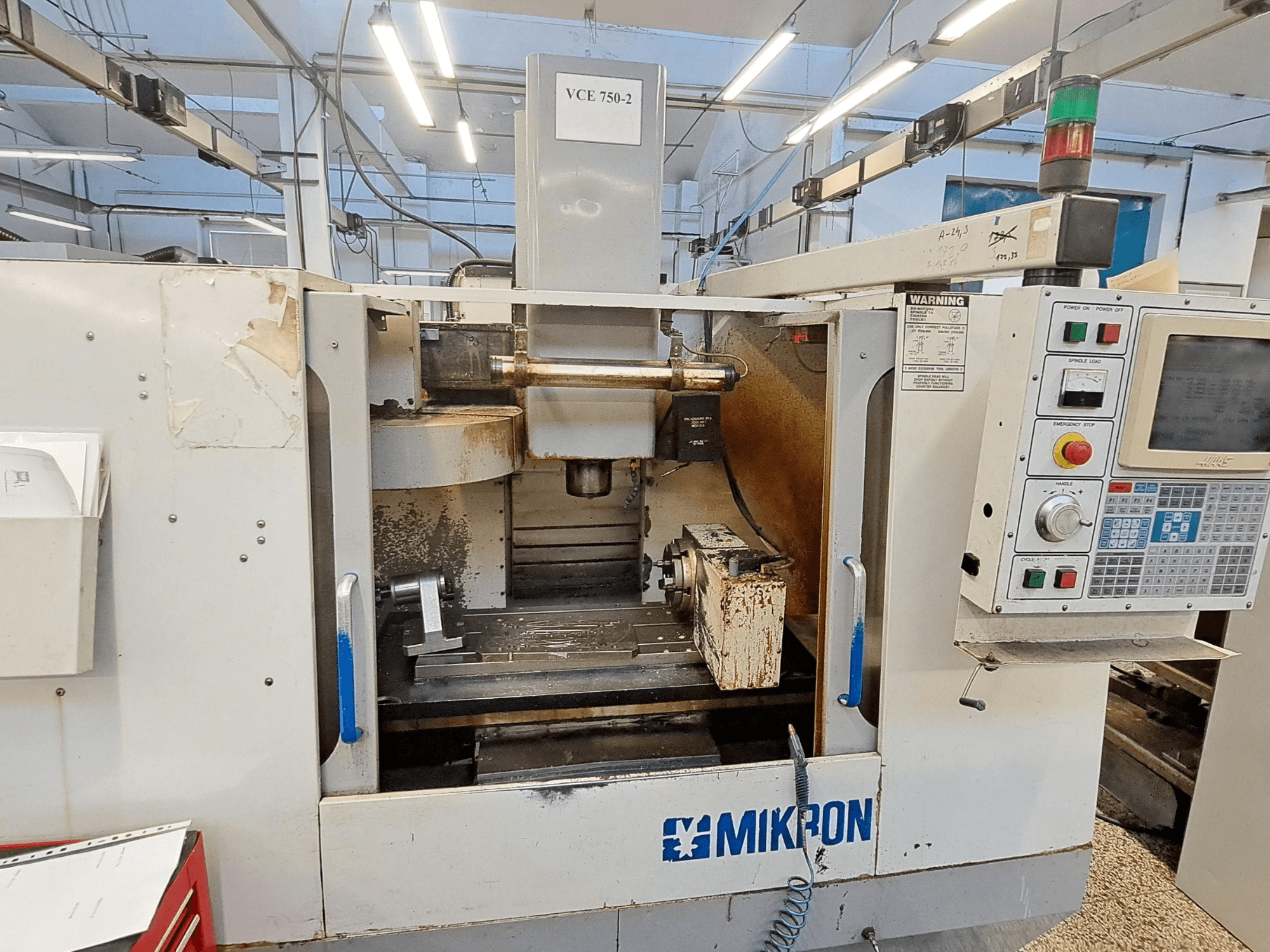 Фрезерний верстат з ЧПК Mikron VCE 750-2, вид спереду, з панеллю керування і шпинделем в зоні обробки, видно знос і забруднення.