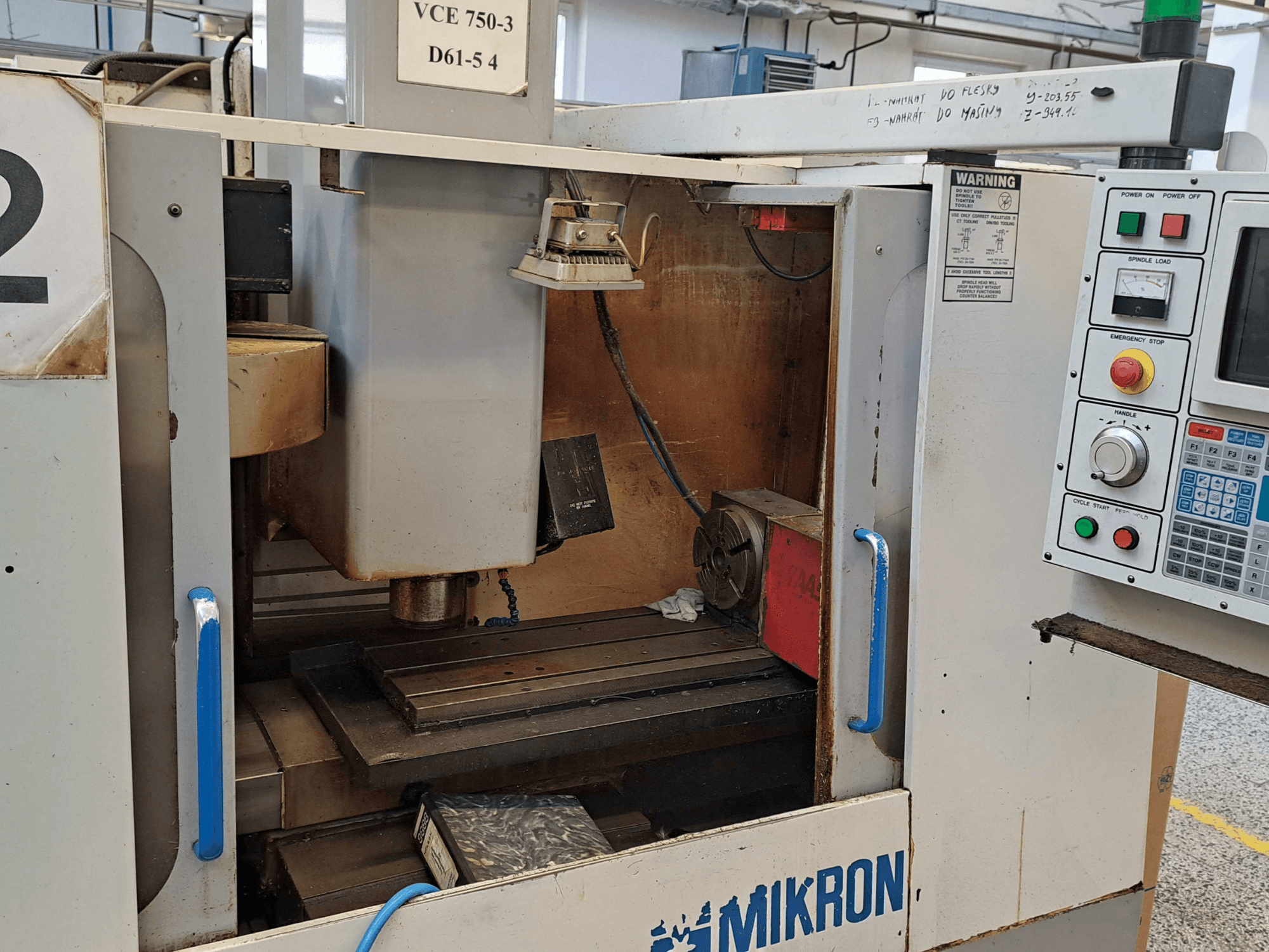 Вид спереду фрезерного верстата Mikron VCE 750-3: шпиндель, панель керування та робочий стіл з технічними деталями.